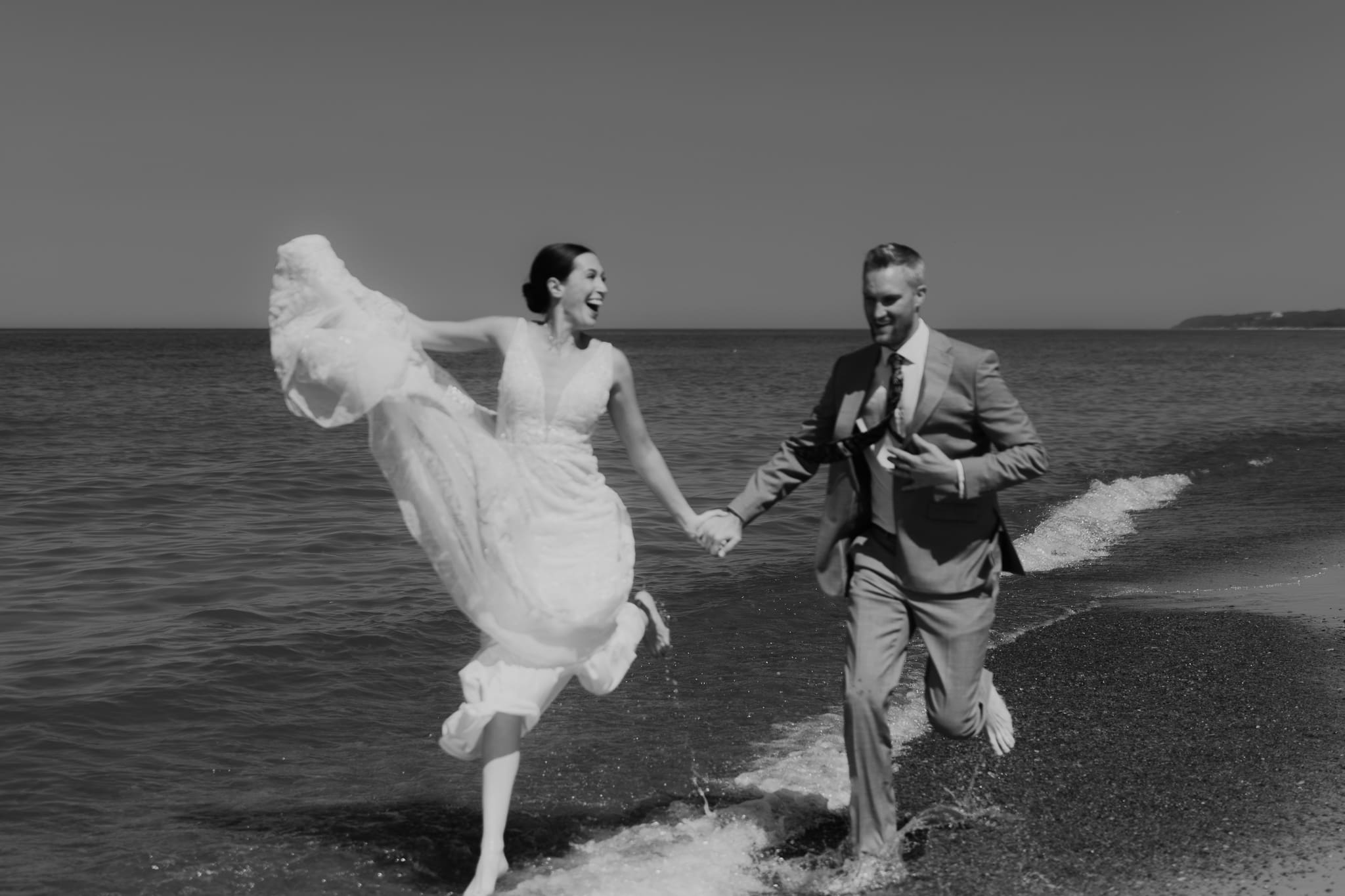 Bride and groom running along the shore of Lake Michigan during their elopement at Warren Dunes State Park