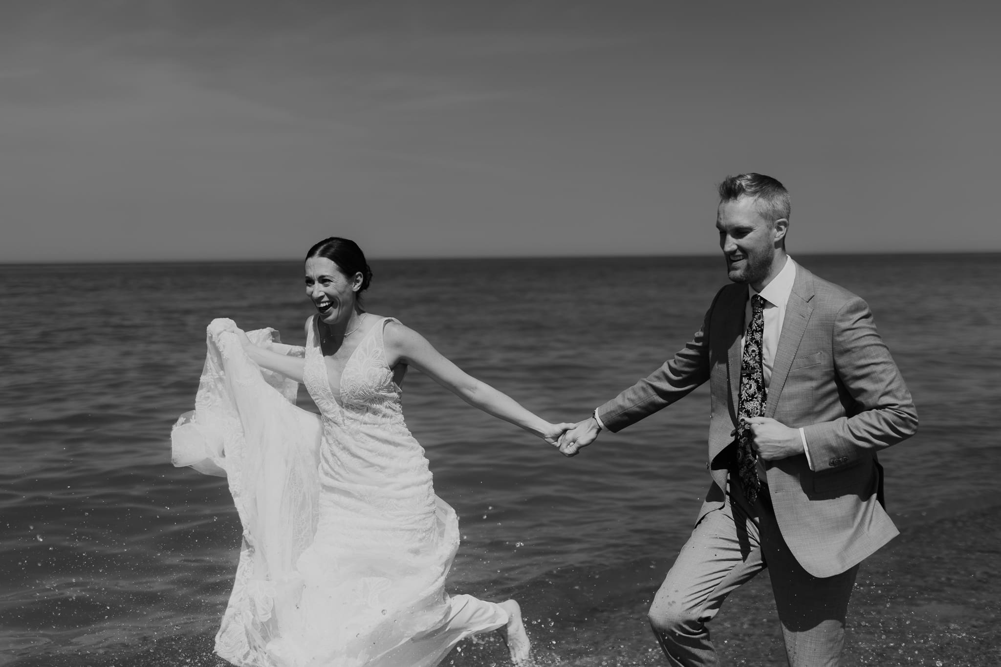 Bride and groom running along the shore of Lake Michigan during their elopement at Warren Dunes State Park