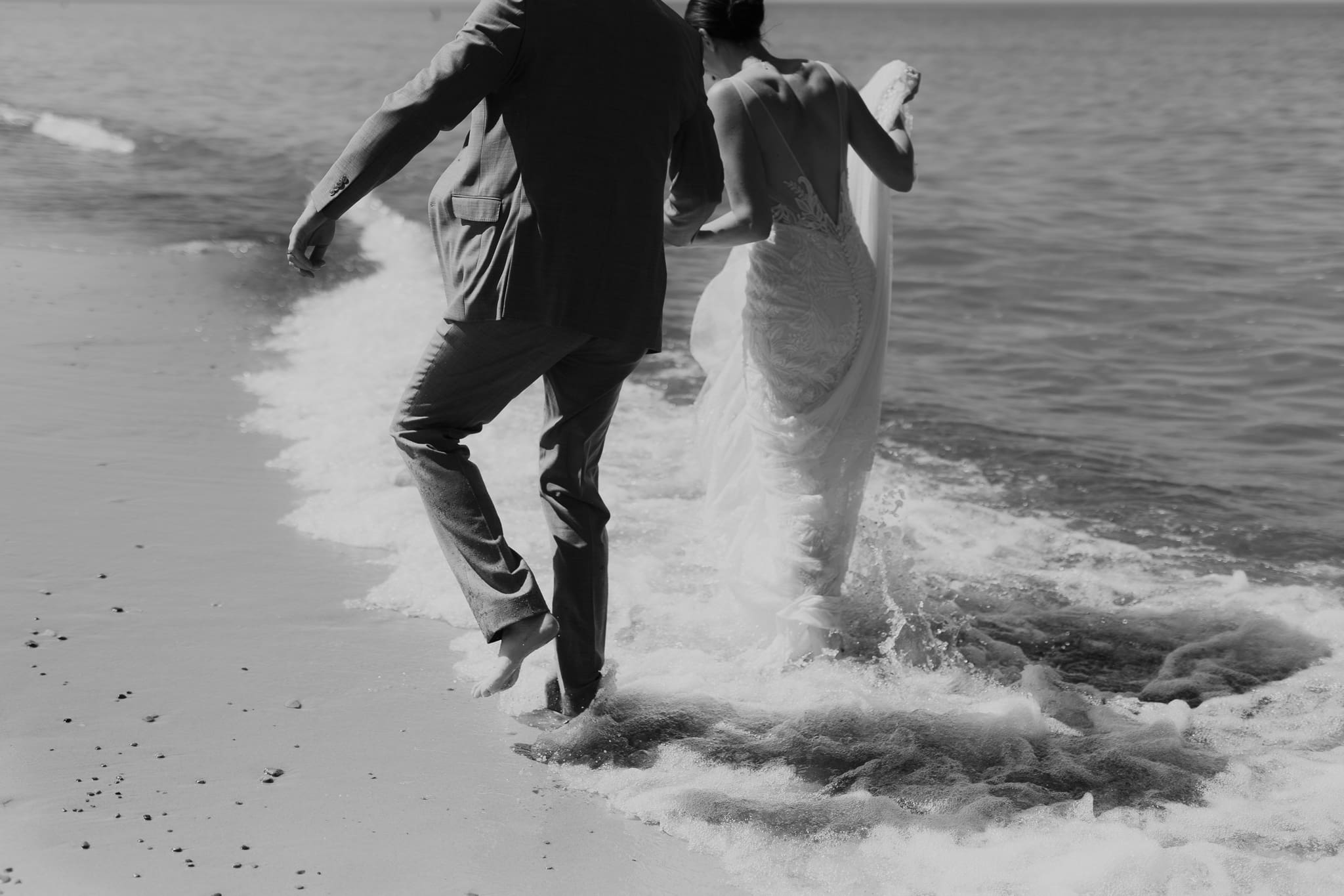 Bride and groom running along the shore of Lake Michigan during their elopement at Warren Dunes State Park
