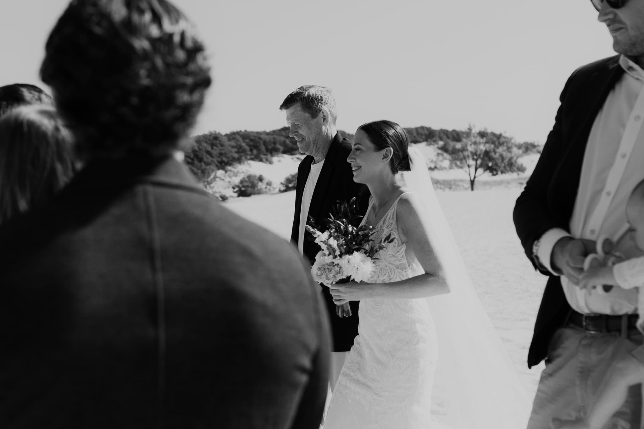 Bride walks down the aisle during a sunny beach wedding at Warren Dunes State Park on Lake Michigan
