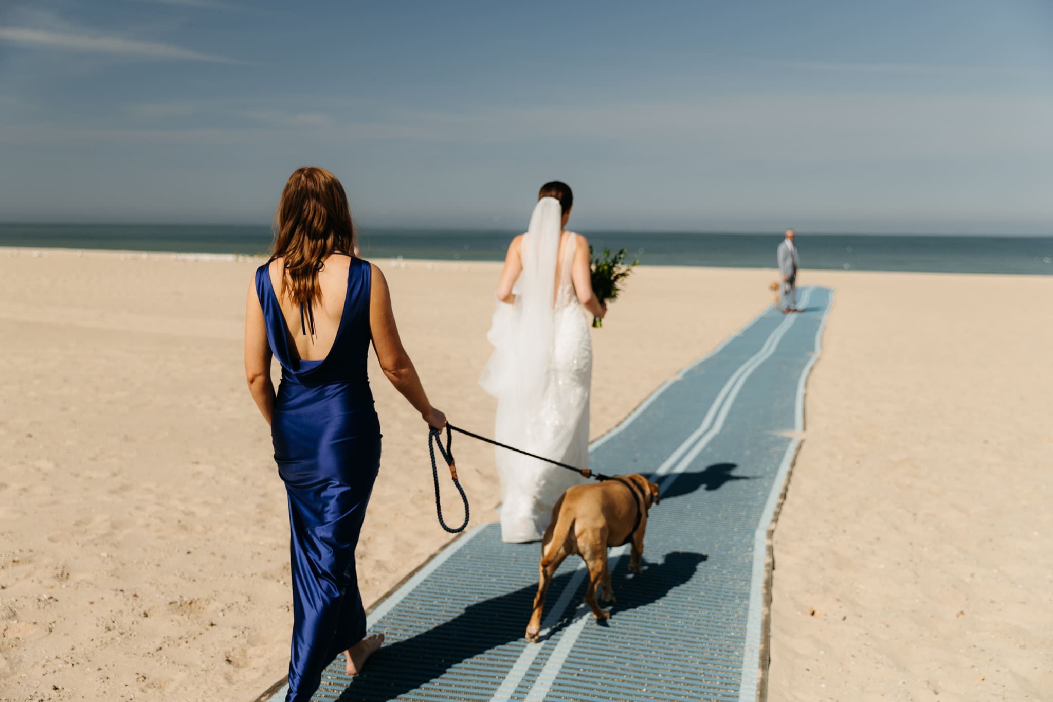 Family and friends walking along the beach towards the wedding ceremony spot at Warren Dunes State Park in Michigan