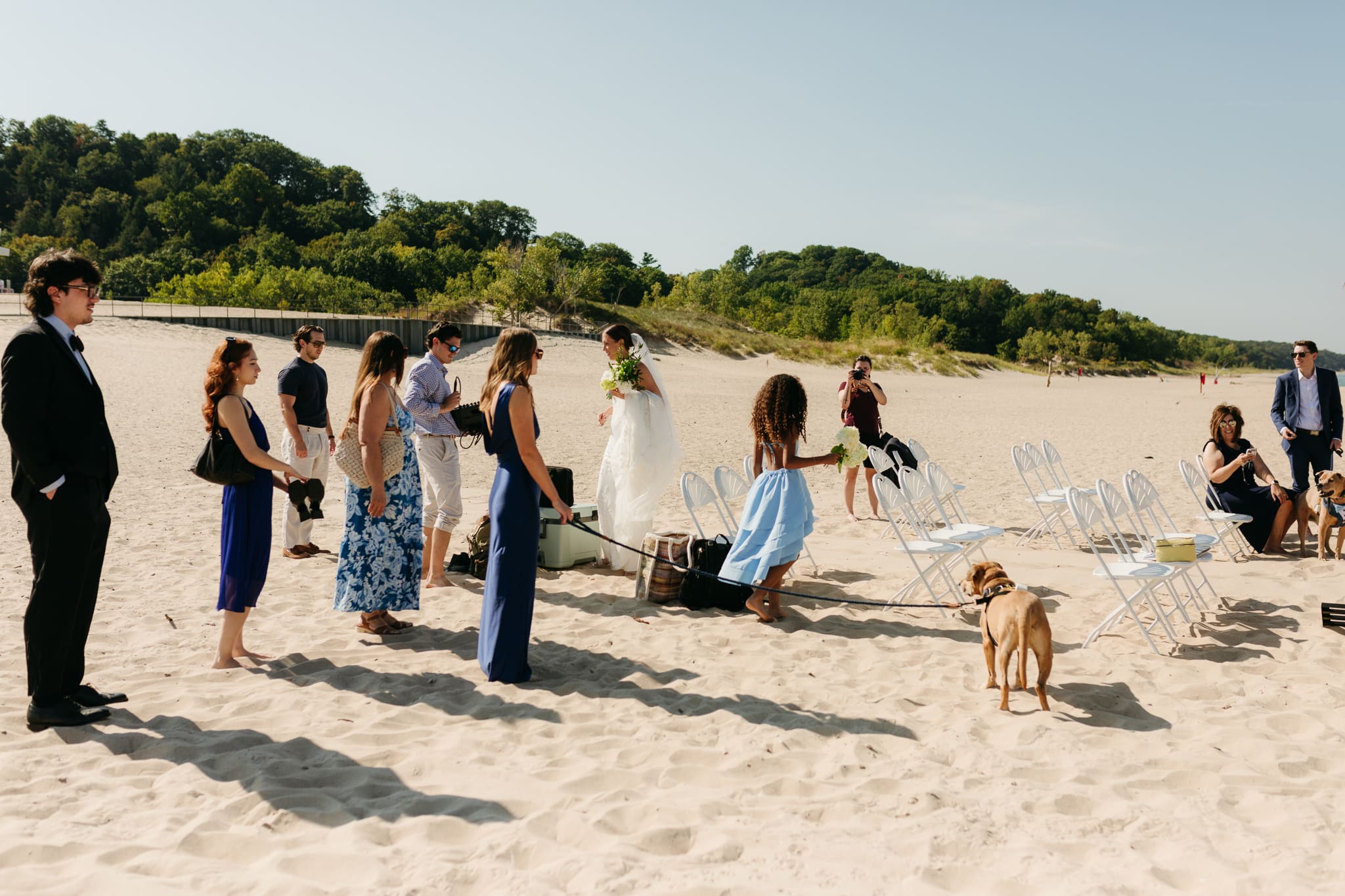 Family and friends walking along the beach towards the wedding ceremony spot at Warren Dunes State Park in Michigan