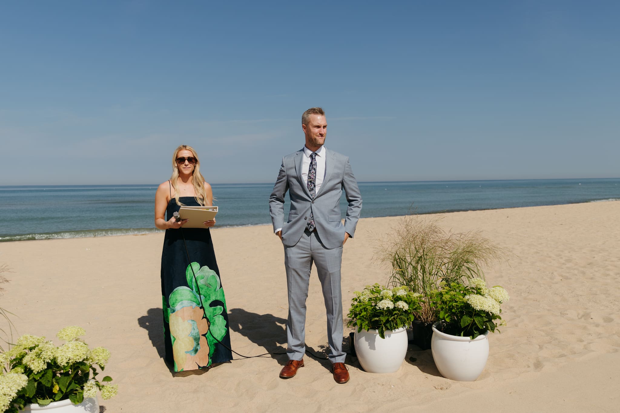Groom waits down the aisle for his bride during a beach wedding ceremony at Warren Dunes State Park