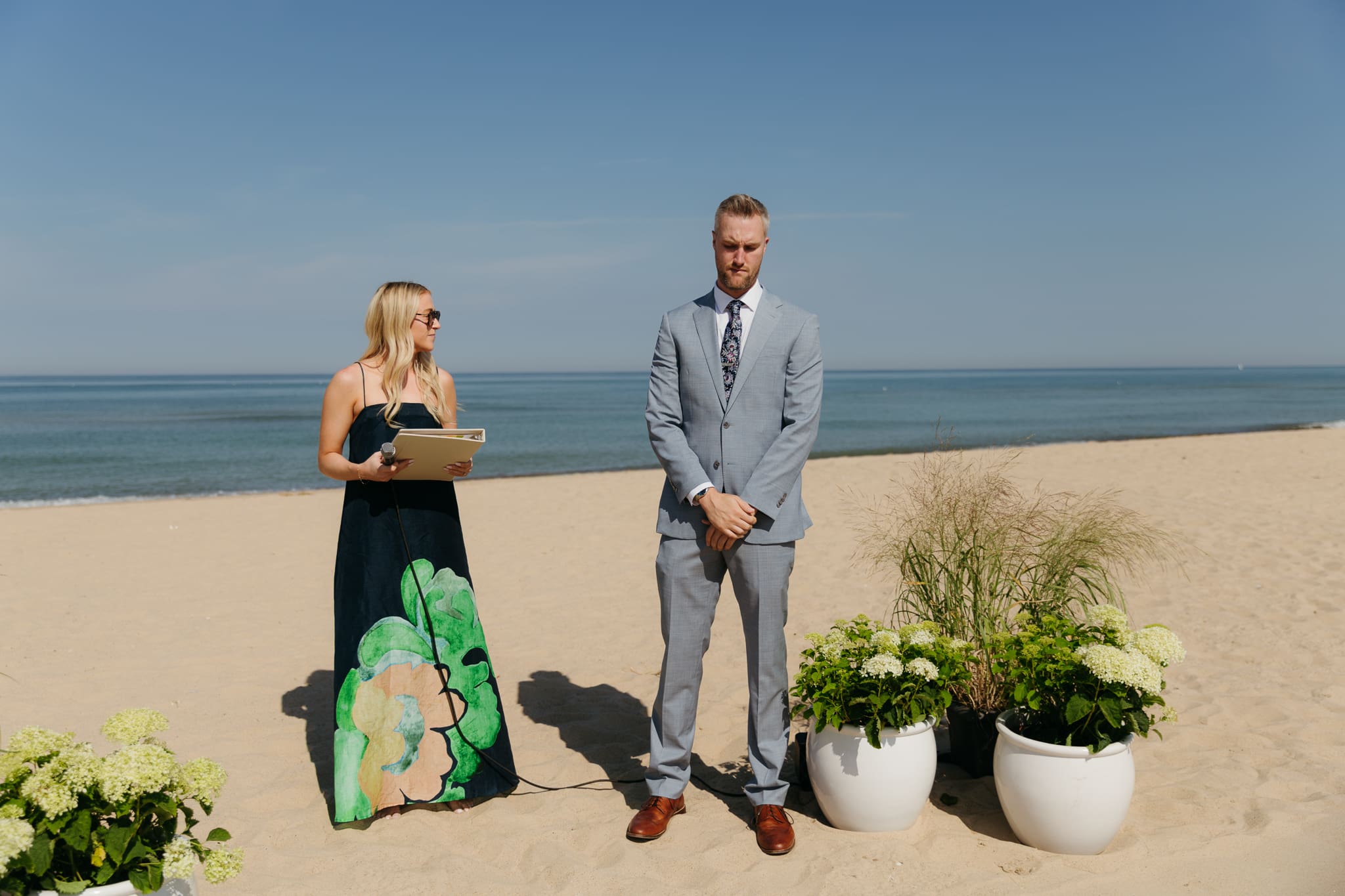 Groom waits down the aisle for his bride during a beach wedding ceremony at Warren Dunes State Park