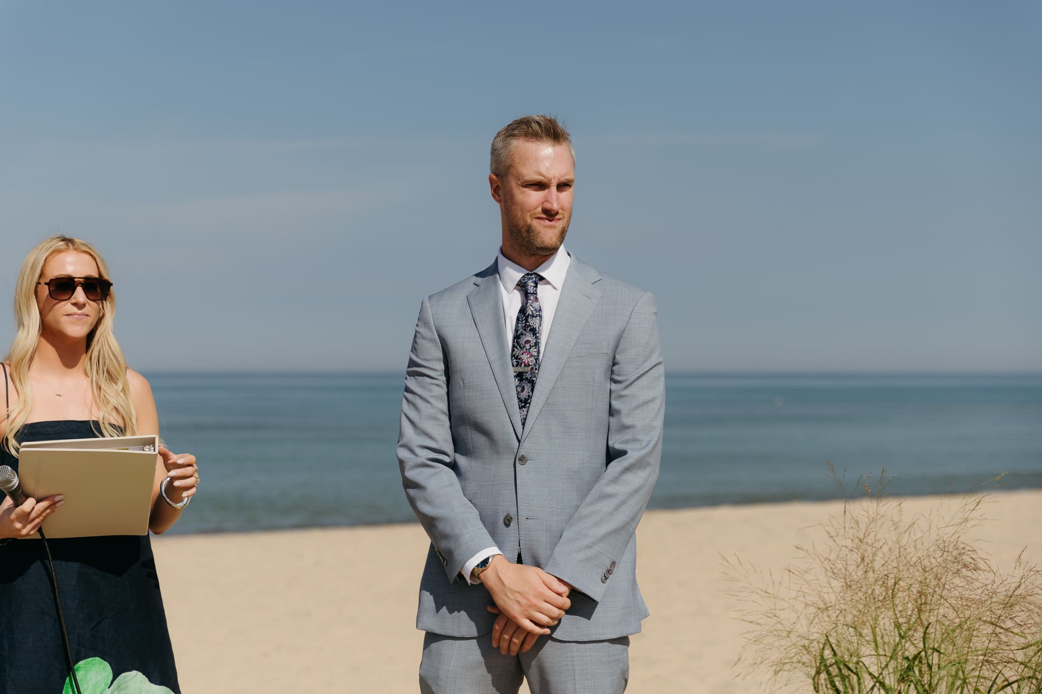 Groom waits down the aisle for his bride during a beach wedding ceremony at Warren Dunes State Park