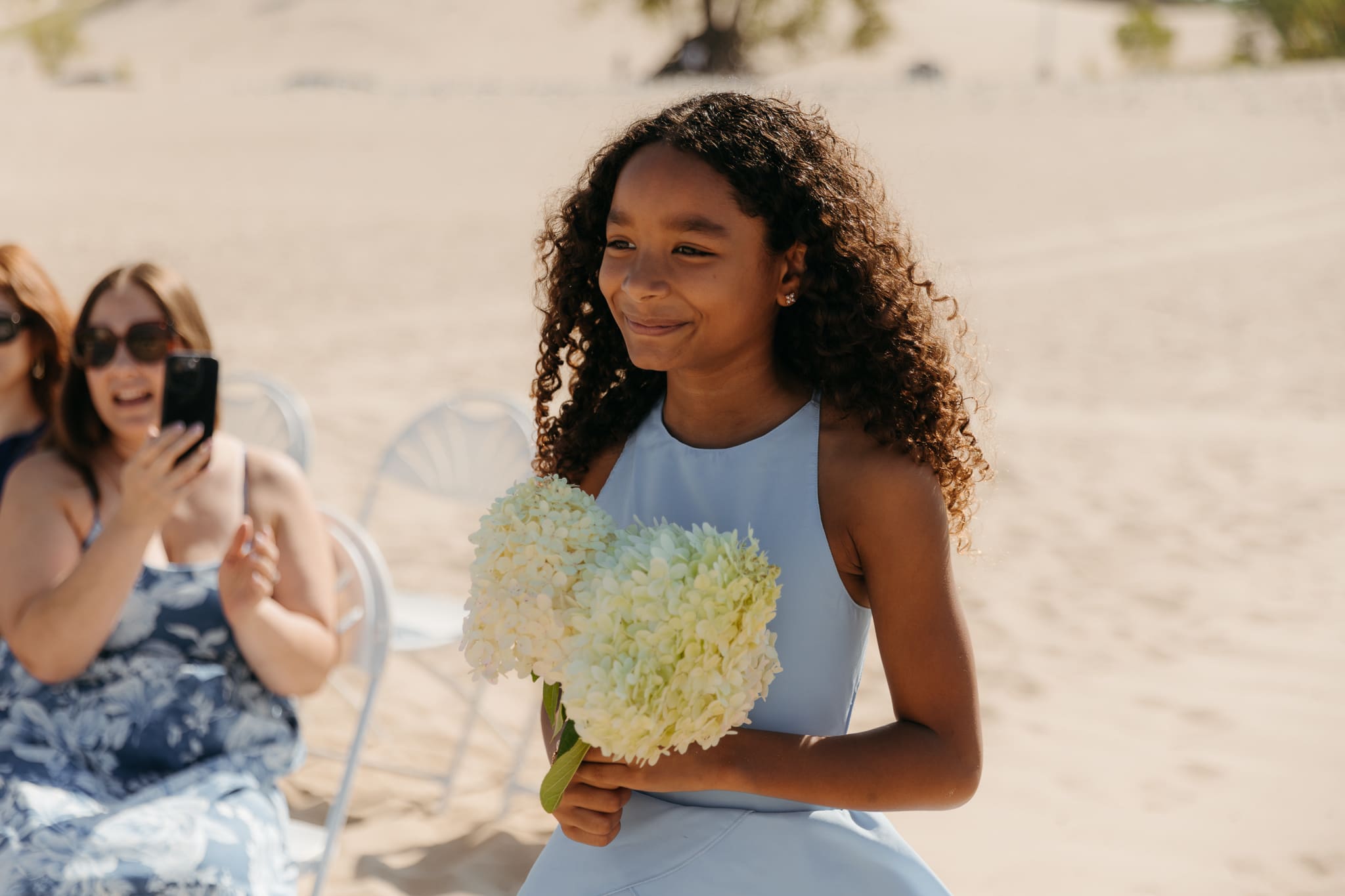 Flower girl walks down the aisle during a sunny beach wedding at Warren Dunes State Park