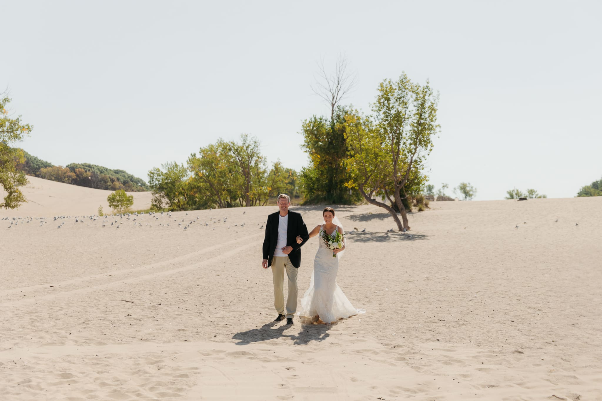 Bride walks down the aisle during a sunny beach wedding at Warren Dunes State Park on Lake Michigan