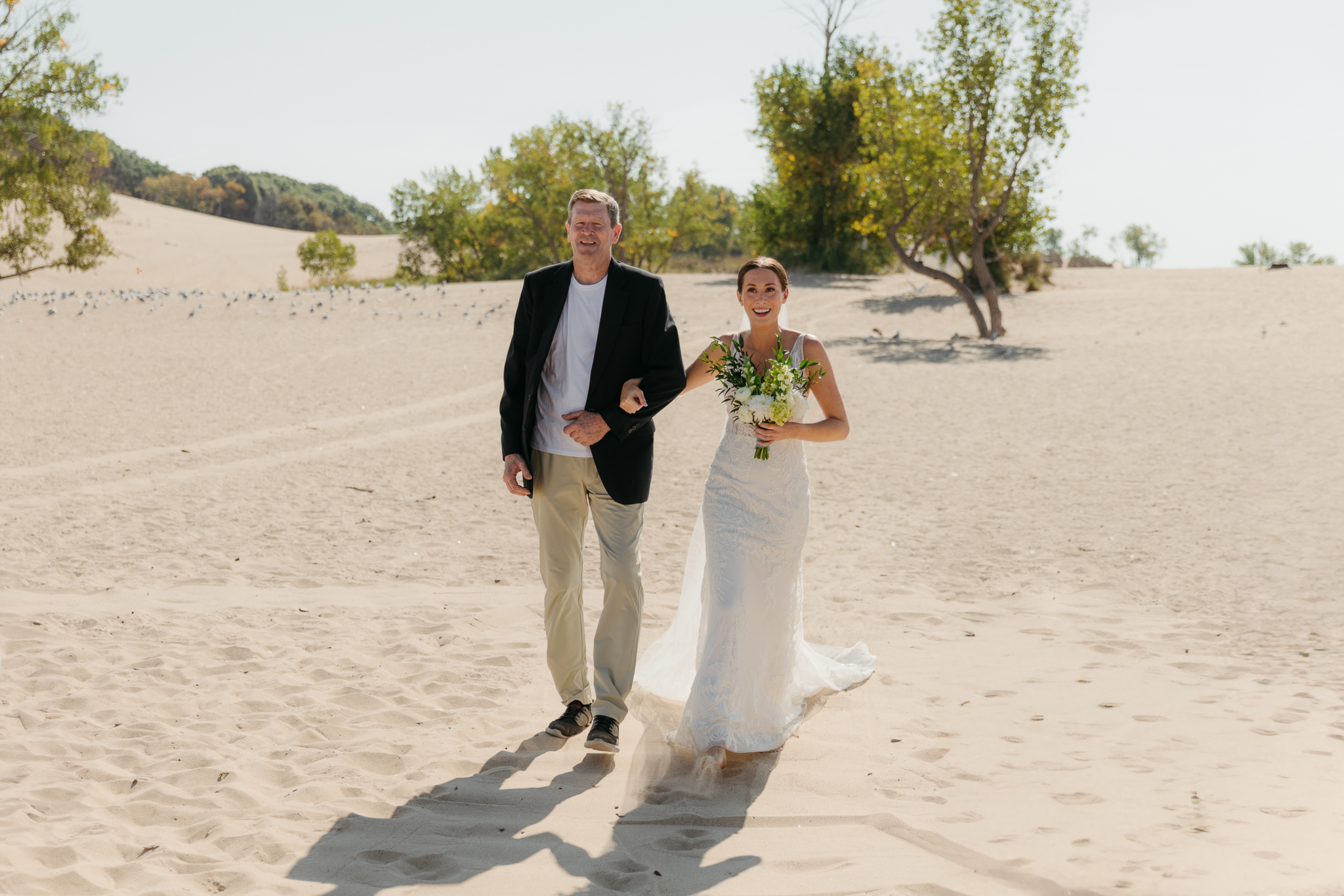 Bride walks down the aisle during a sunny beach wedding at Warren Dunes State Park on Lake Michigan