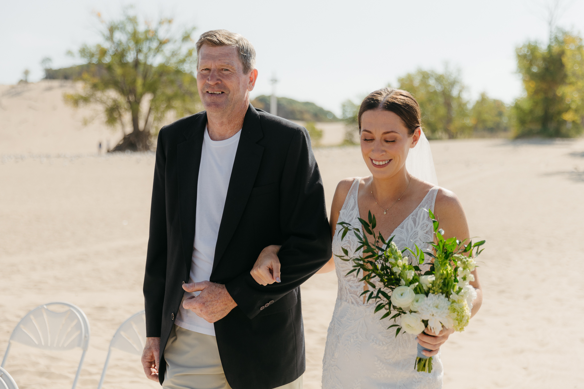Bride walks down the aisle during a sunny beach wedding at Warren Dunes State Park on Lake Michigan