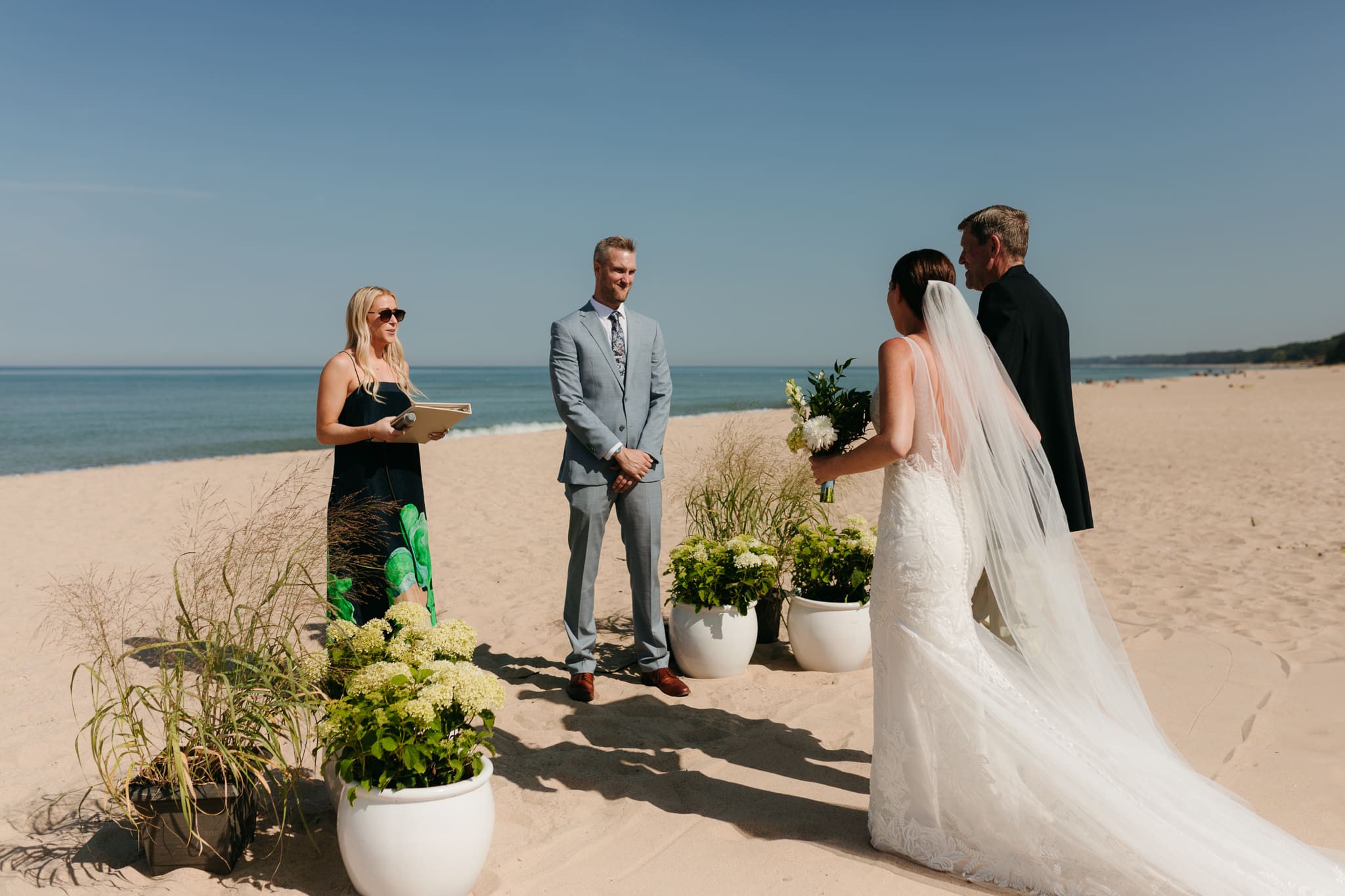Bride walks down the aisle during a sunny beach wedding at Warren Dunes State Park on Lake Michigan