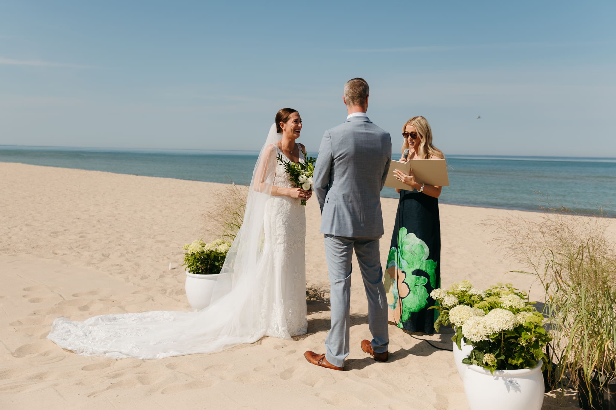 Bride and groom exchange vows on the beach during their Lake Michigan wedding ceremony at Warren Dunes State Park