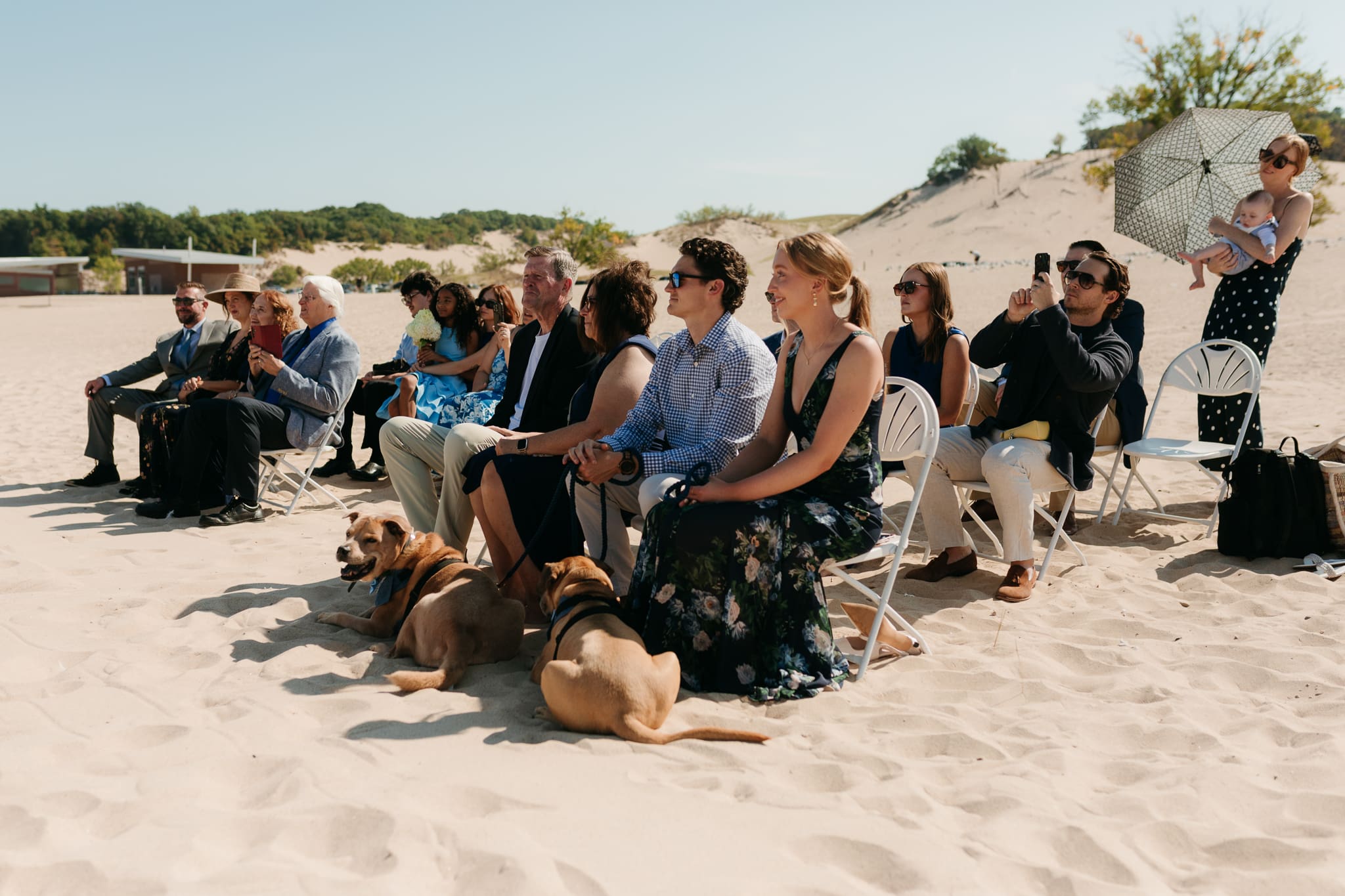 Wedding guests watch as bride and groom exchange vows on the beach during their Lake Michigan wedding ceremony at Warren Dunes State Park