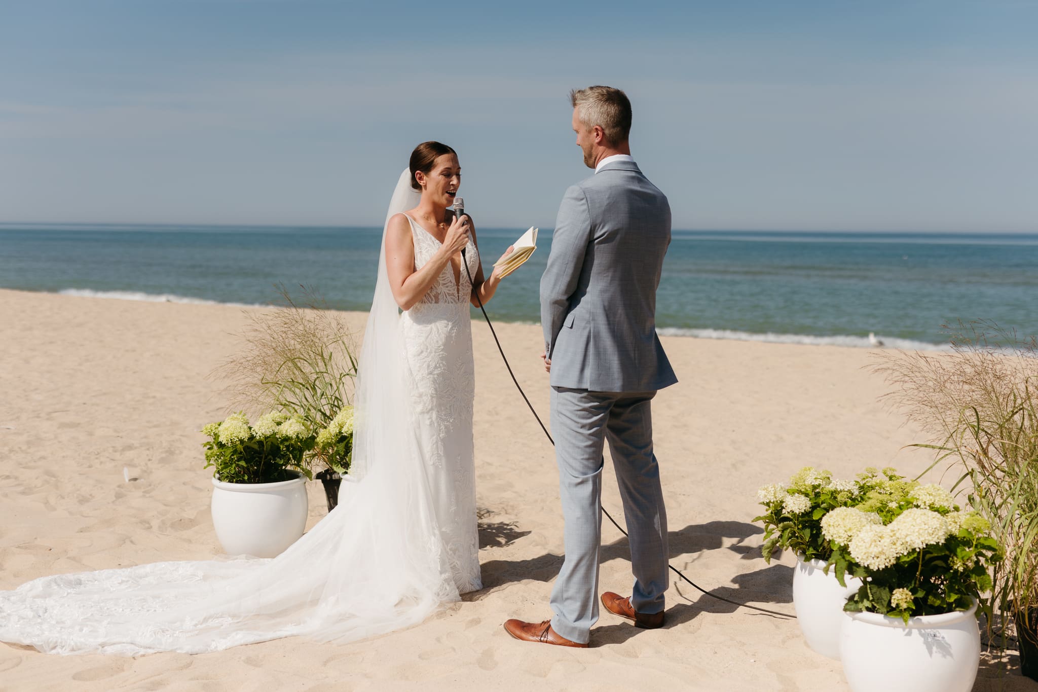 Bride and groom exchange vows on the beach during their Lake Michigan wedding ceremony at Warren Dunes State Park