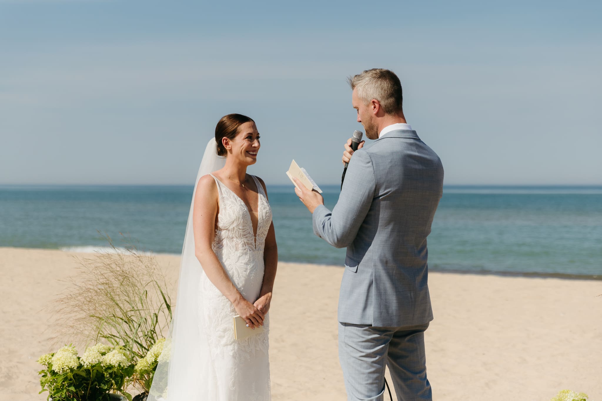 Bride and groom exchange vows on the beach during their Lake Michigan wedding ceremony at Warren Dunes State Park
