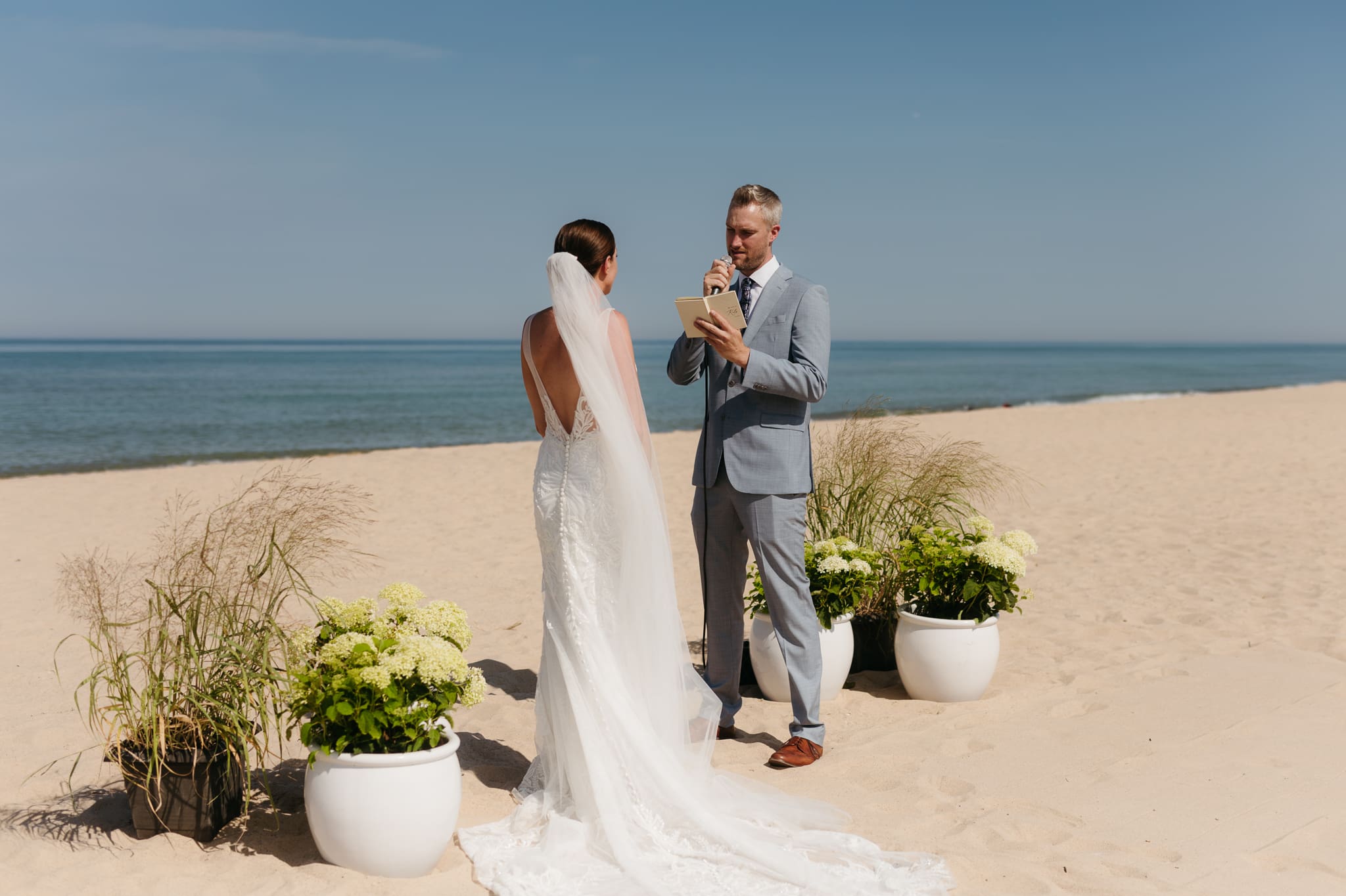 Bride and groom exchange vows on the beach during their Lake Michigan wedding ceremony at Warren Dunes State Park