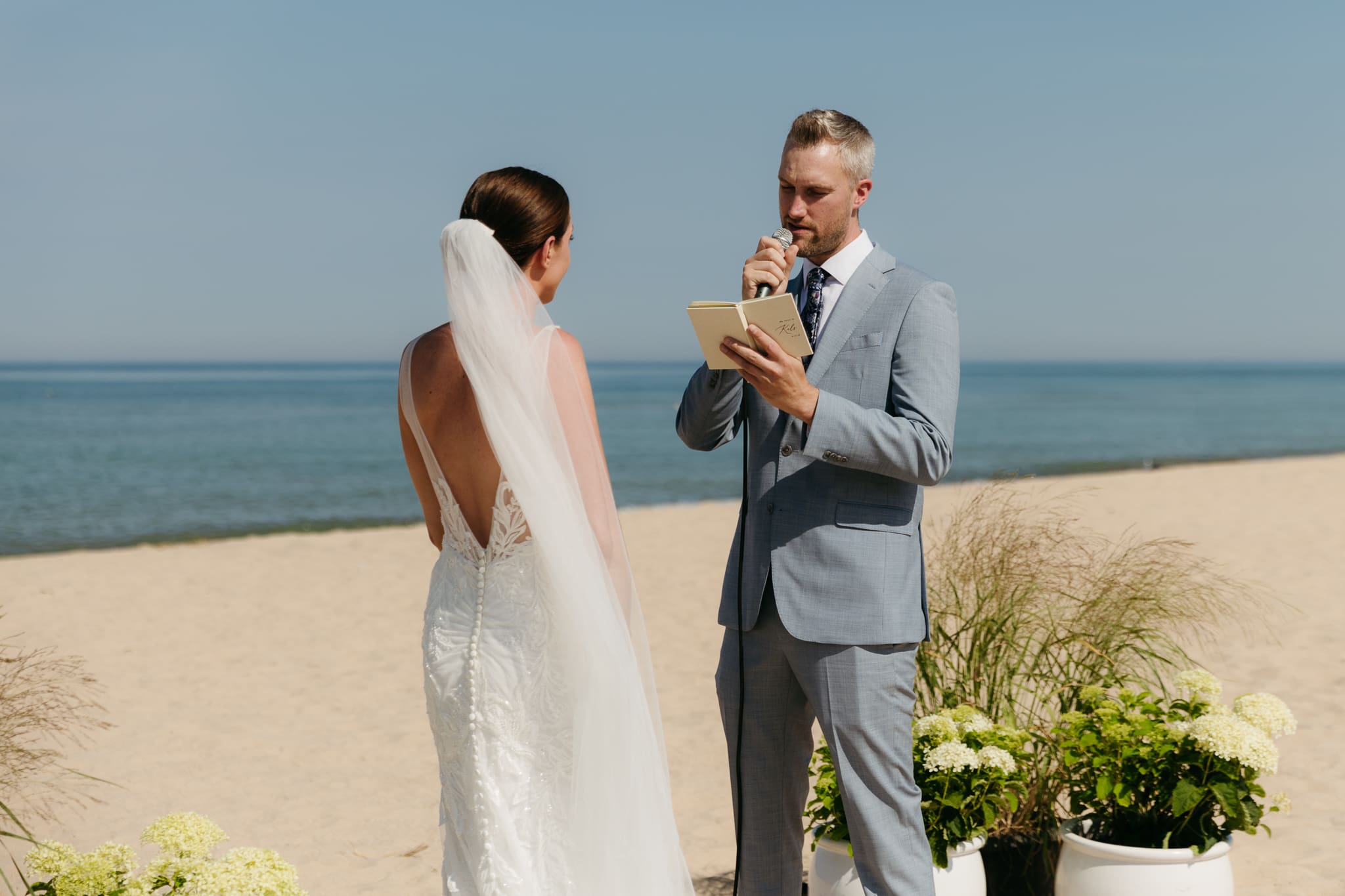 Bride and groom exchange vows on the beach during their Lake Michigan wedding ceremony at Warren Dunes State Park