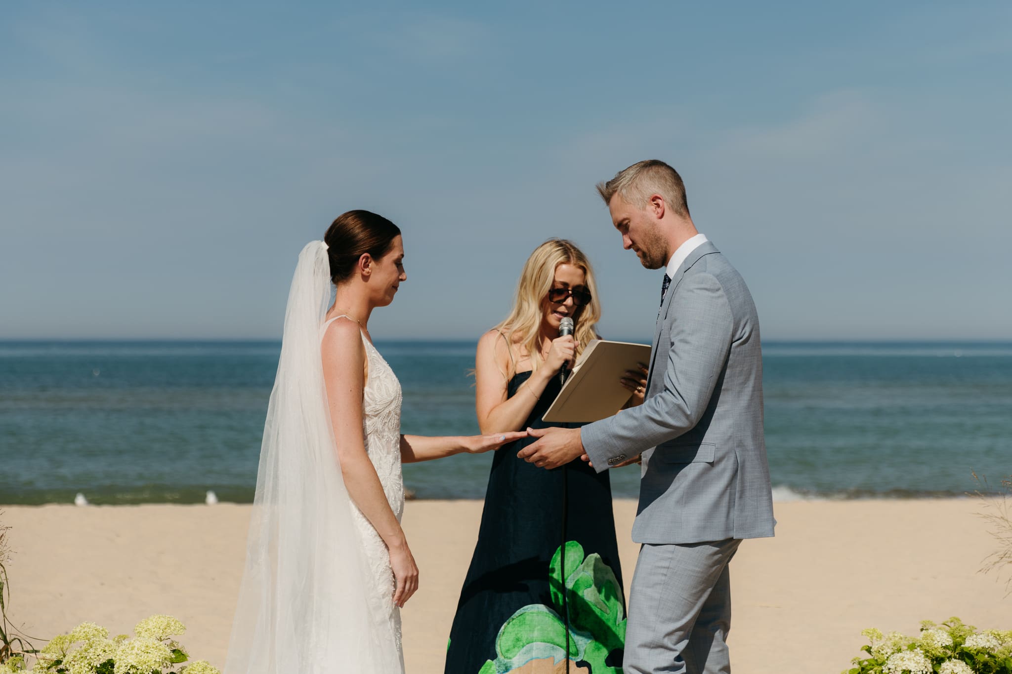 Bride and groom exchange vows and rings on the beach during their Lake Michigan wedding ceremony at Warren Dunes State Park