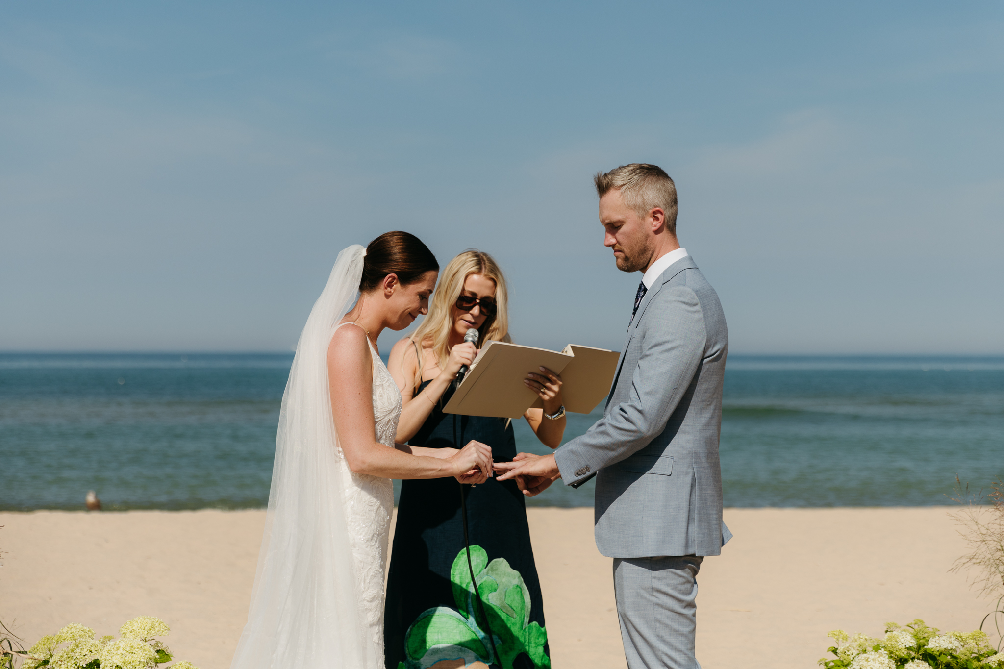 Bride and groom exchange vows and rings on the beach during their Lake Michigan wedding ceremony at Warren Dunes State Park