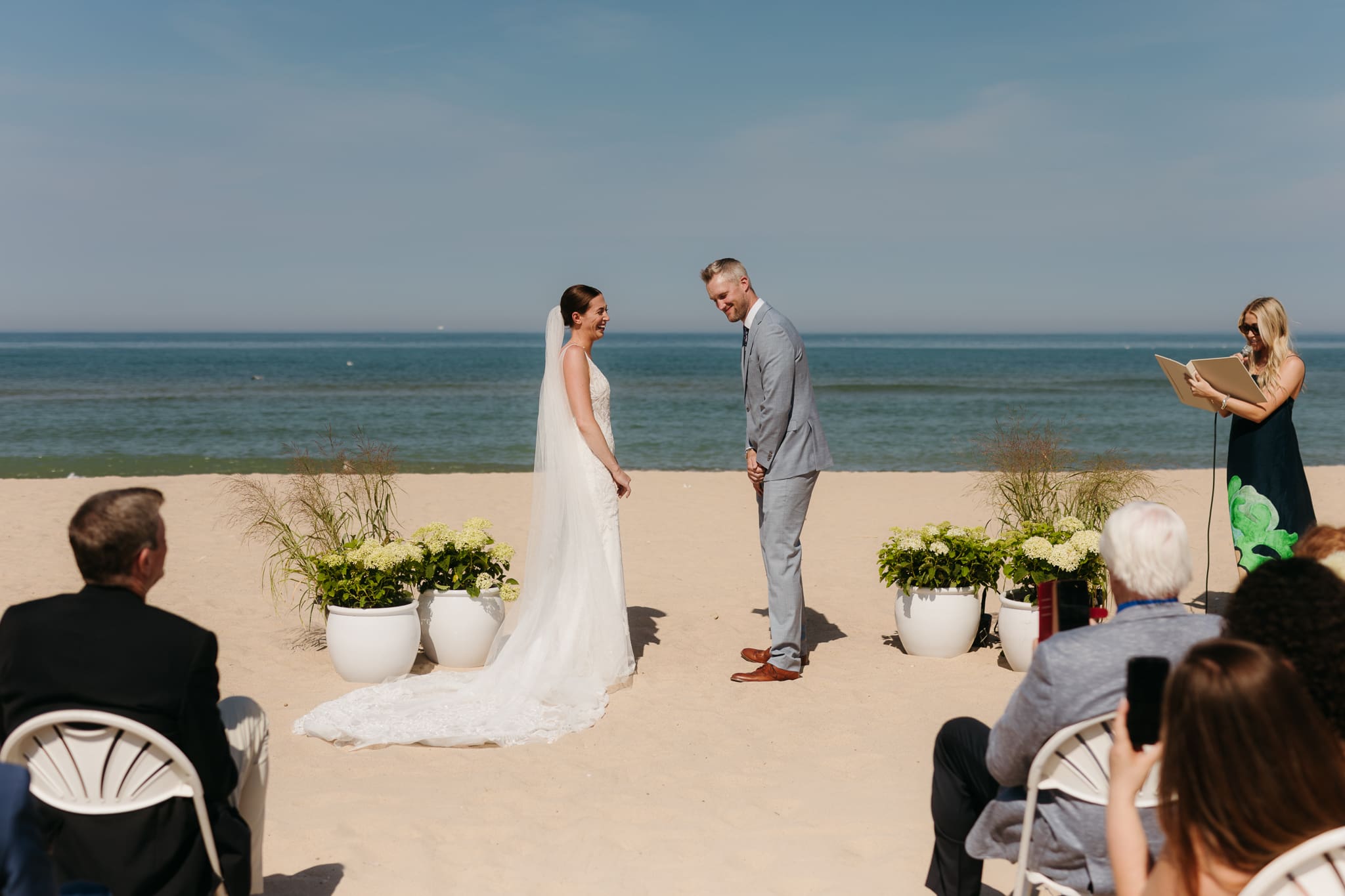 Bride and groom exchange vows and rings on the beach during their Lake Michigan wedding ceremony at Warren Dunes State Park