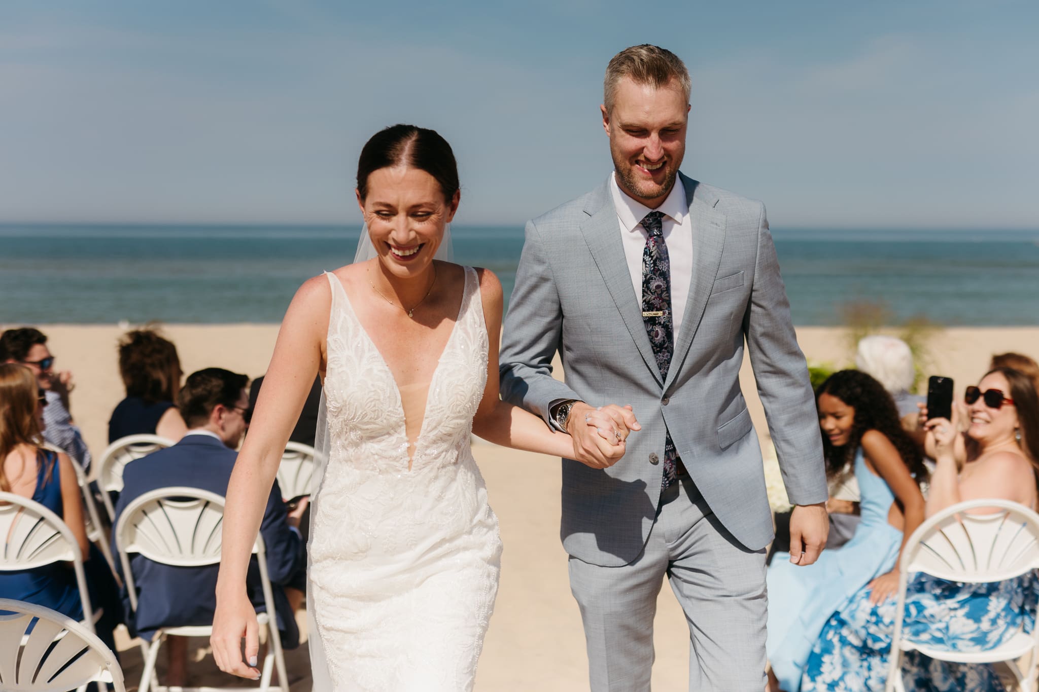 Bride and groom embrace and celebrate after sealing their wedding ceremony with a first kiss, during their Lake Michigan beach wedding