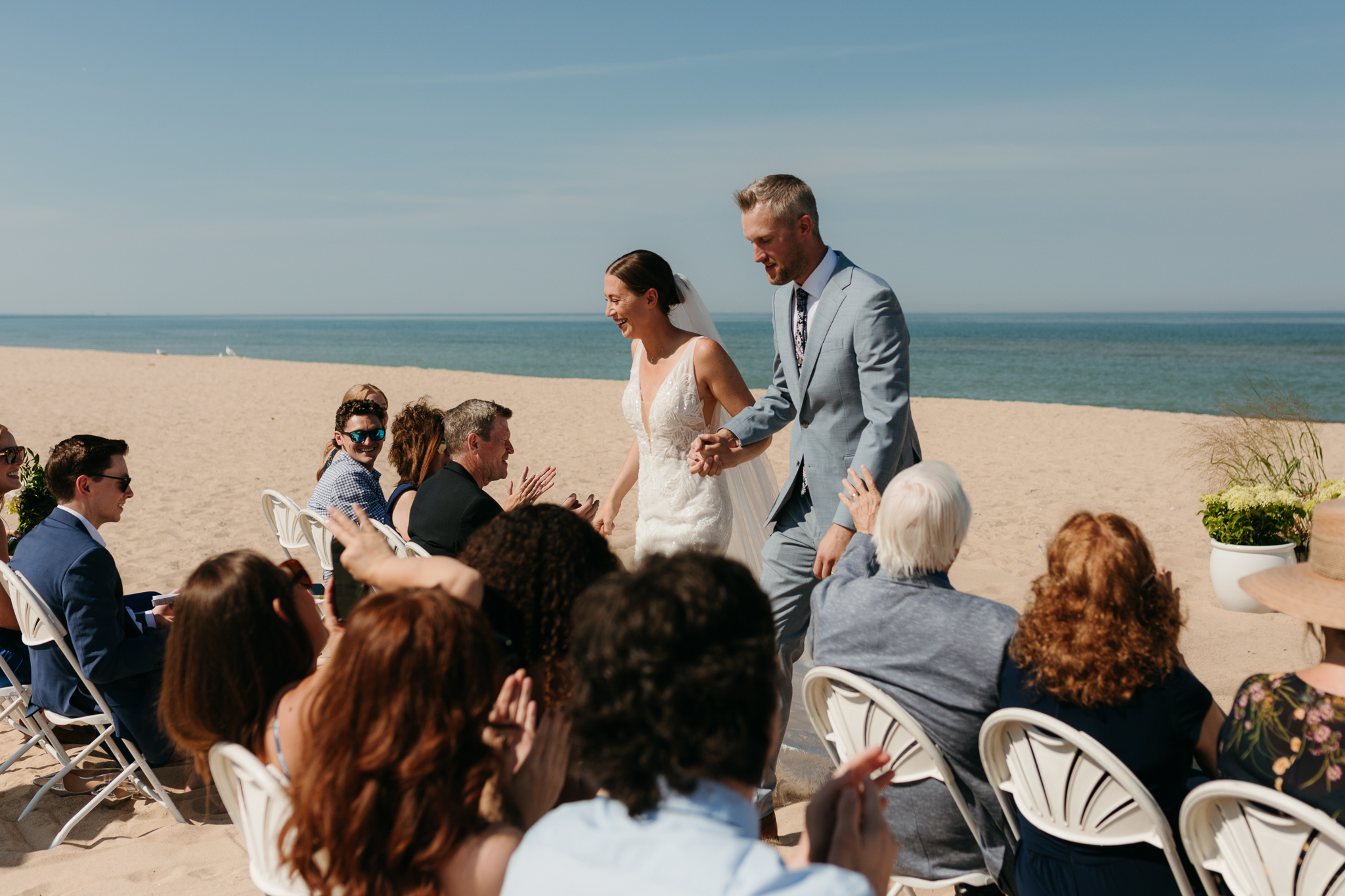 Bride and groom embrace and celebrate after sealing their wedding ceremony with a first kiss, during their Lake Michigan beach wedding