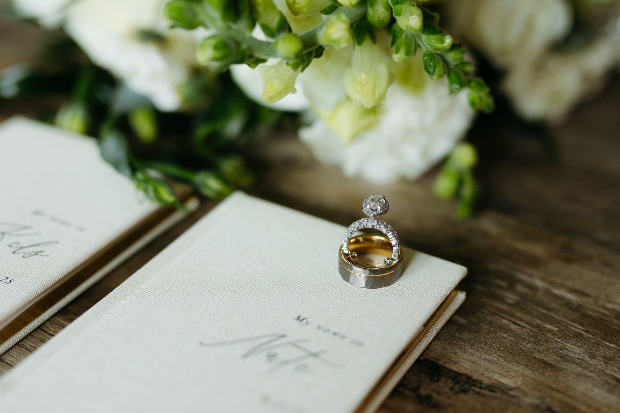 Wedding vow books with wedding rings and bouquet of flowers for a beach elopement at Warren Dunes