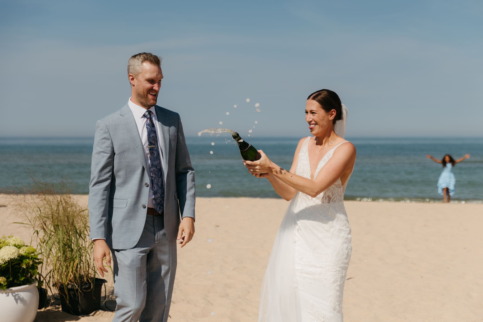 Bride and groom pop champagne for a toast with wedding guests at their Warren Dunes elopement
