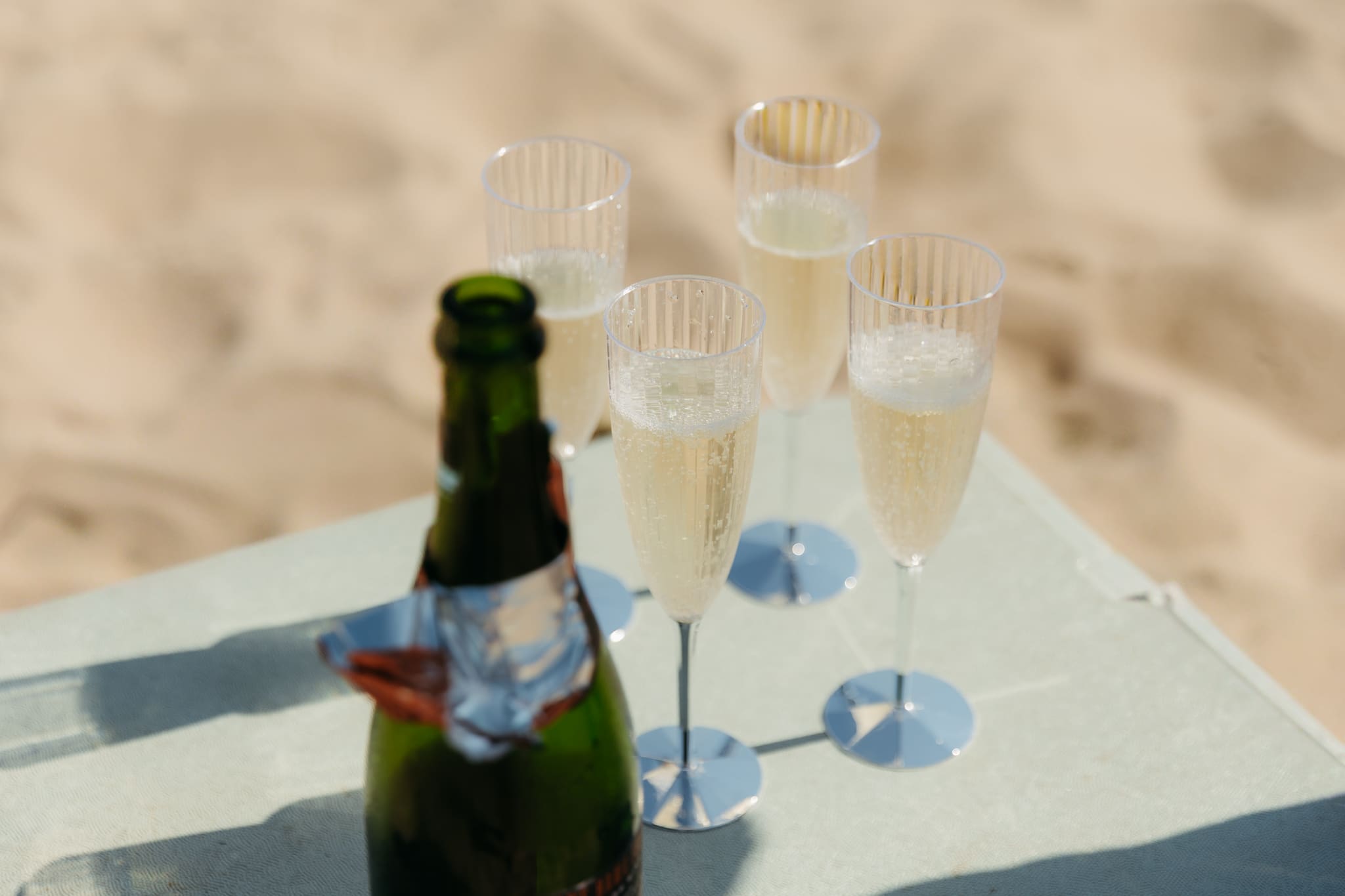 Bride and groom pop champagne for a toast with wedding guests at their Warren Dunes elopement