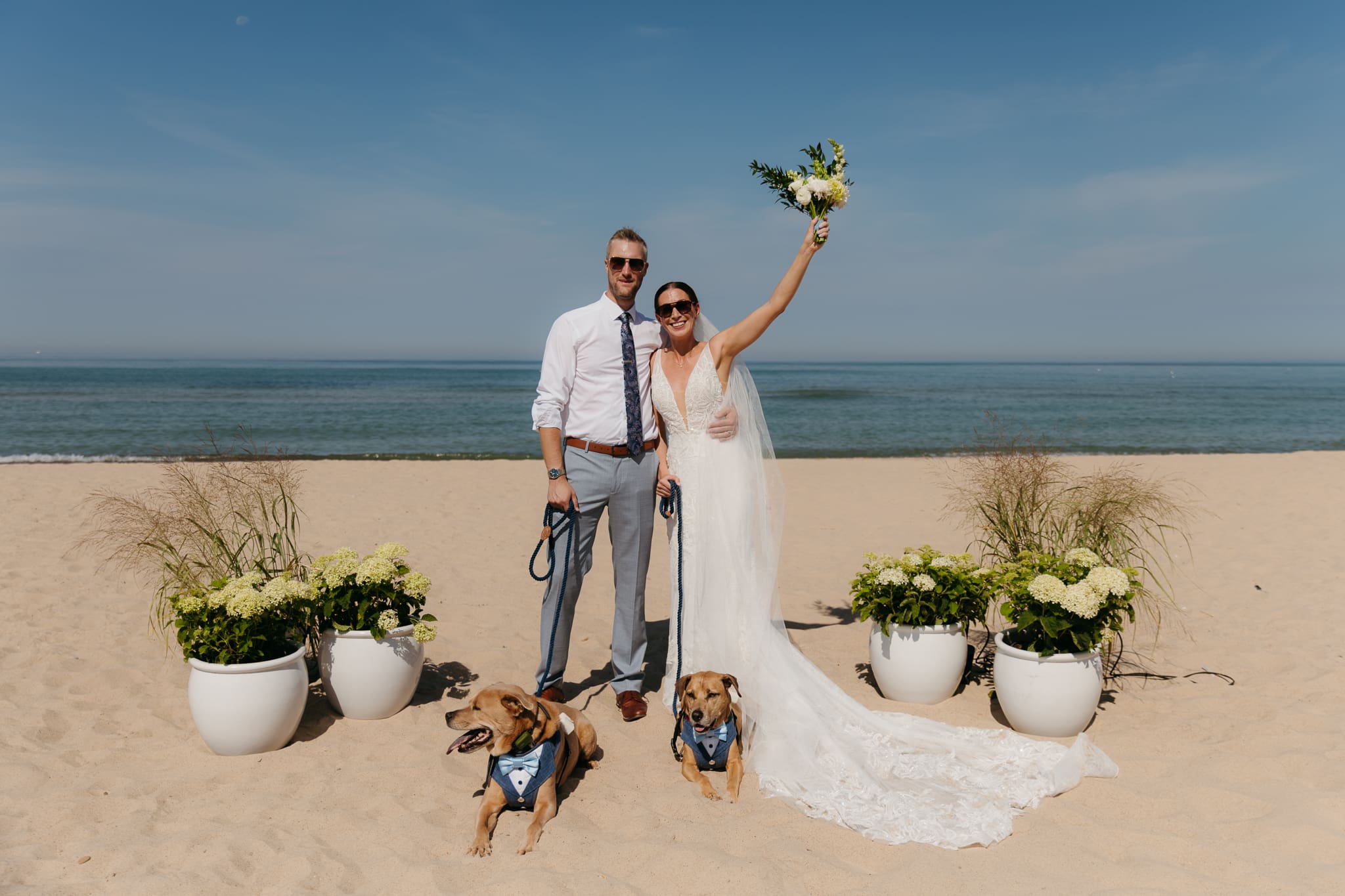 Bride and groom smiling and posing with their dogs after getting married on the Warren Dunes State Park Beach
