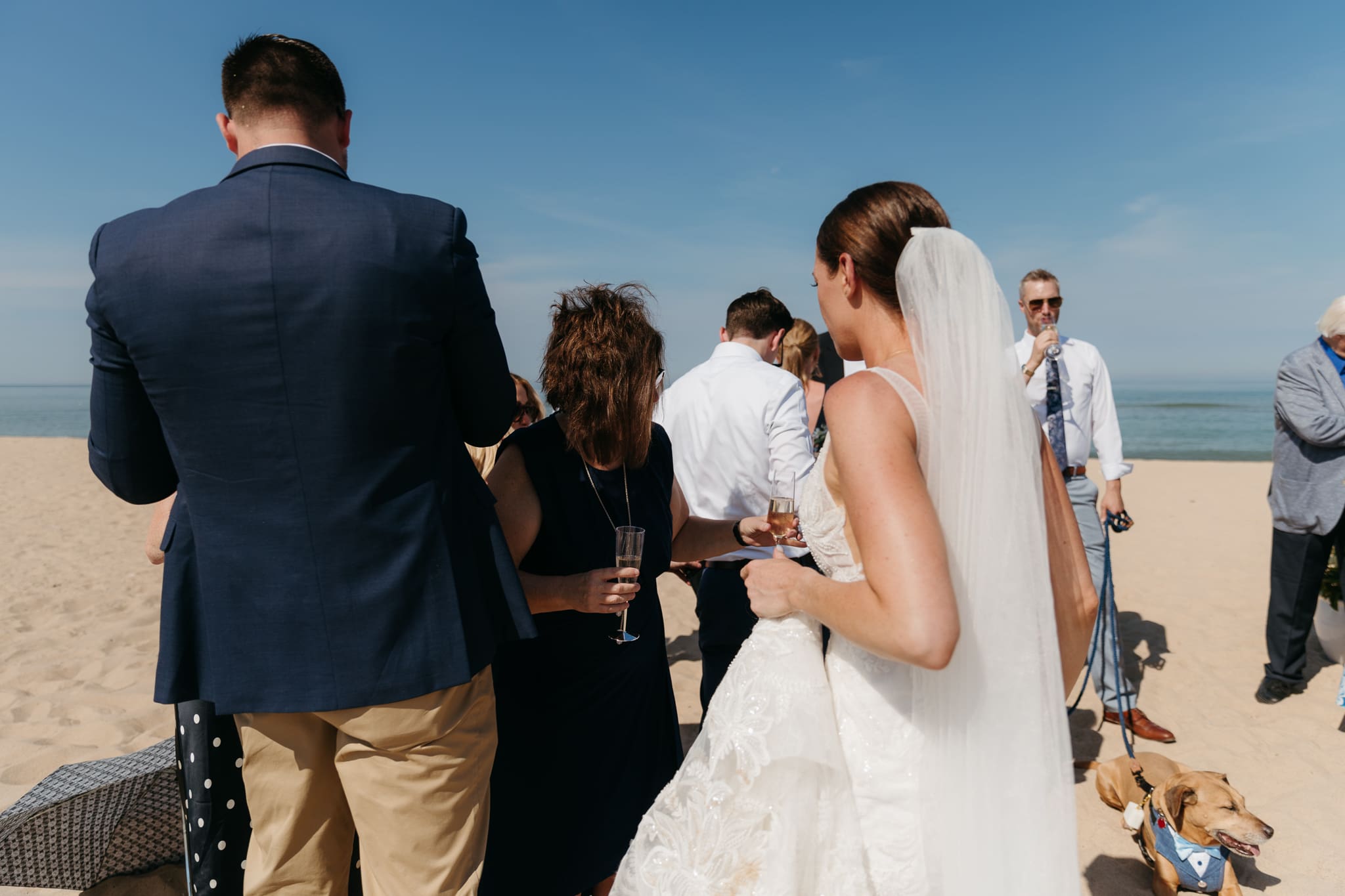 Bride and groom share champagne with guests and toast as a celebration of their marriage during their Warren Dunes elopement along the beach