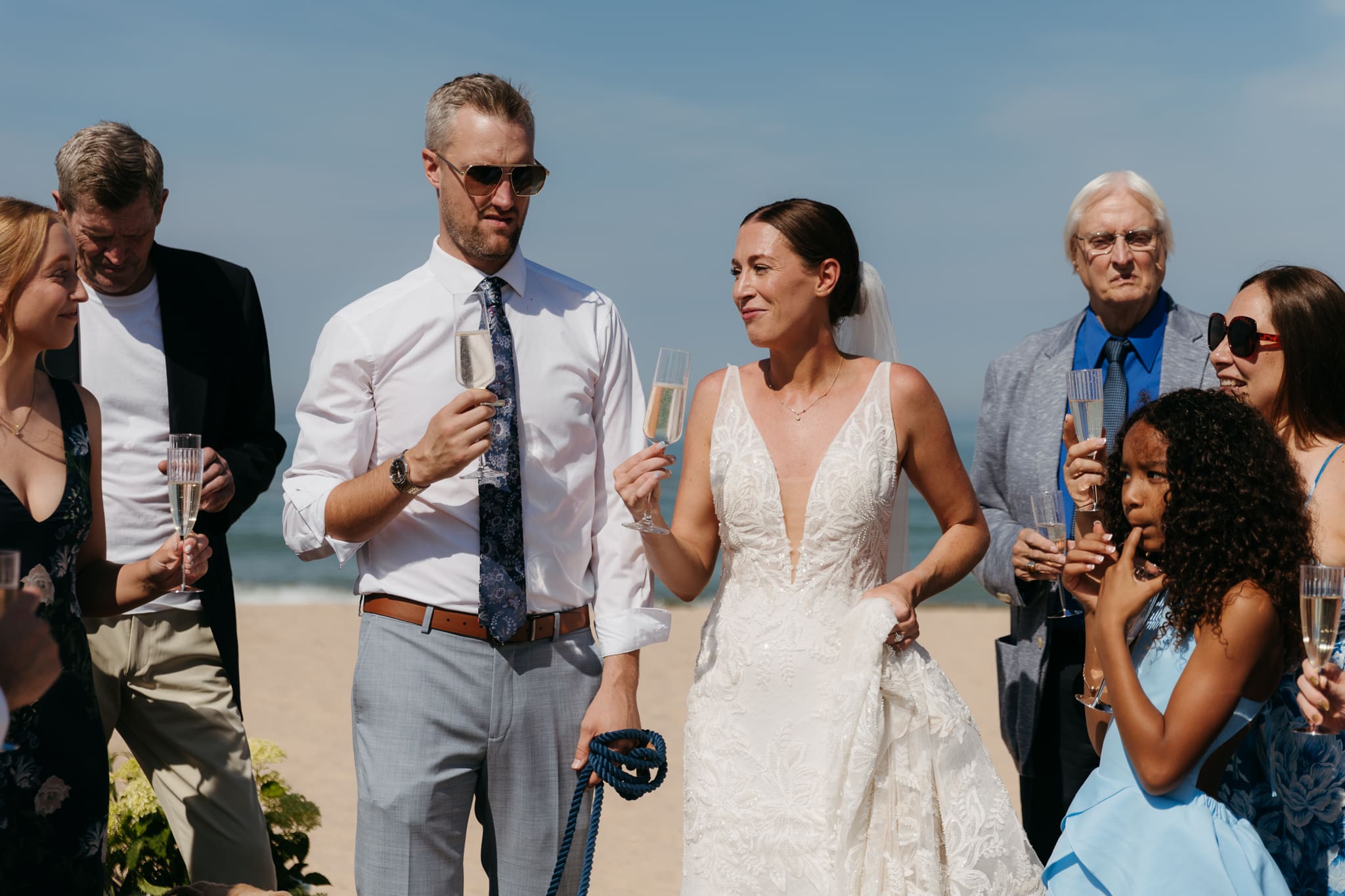 Bride and groom share champagne with guests and toast as a celebration of their marriage during their Warren Dunes elopement along the beach