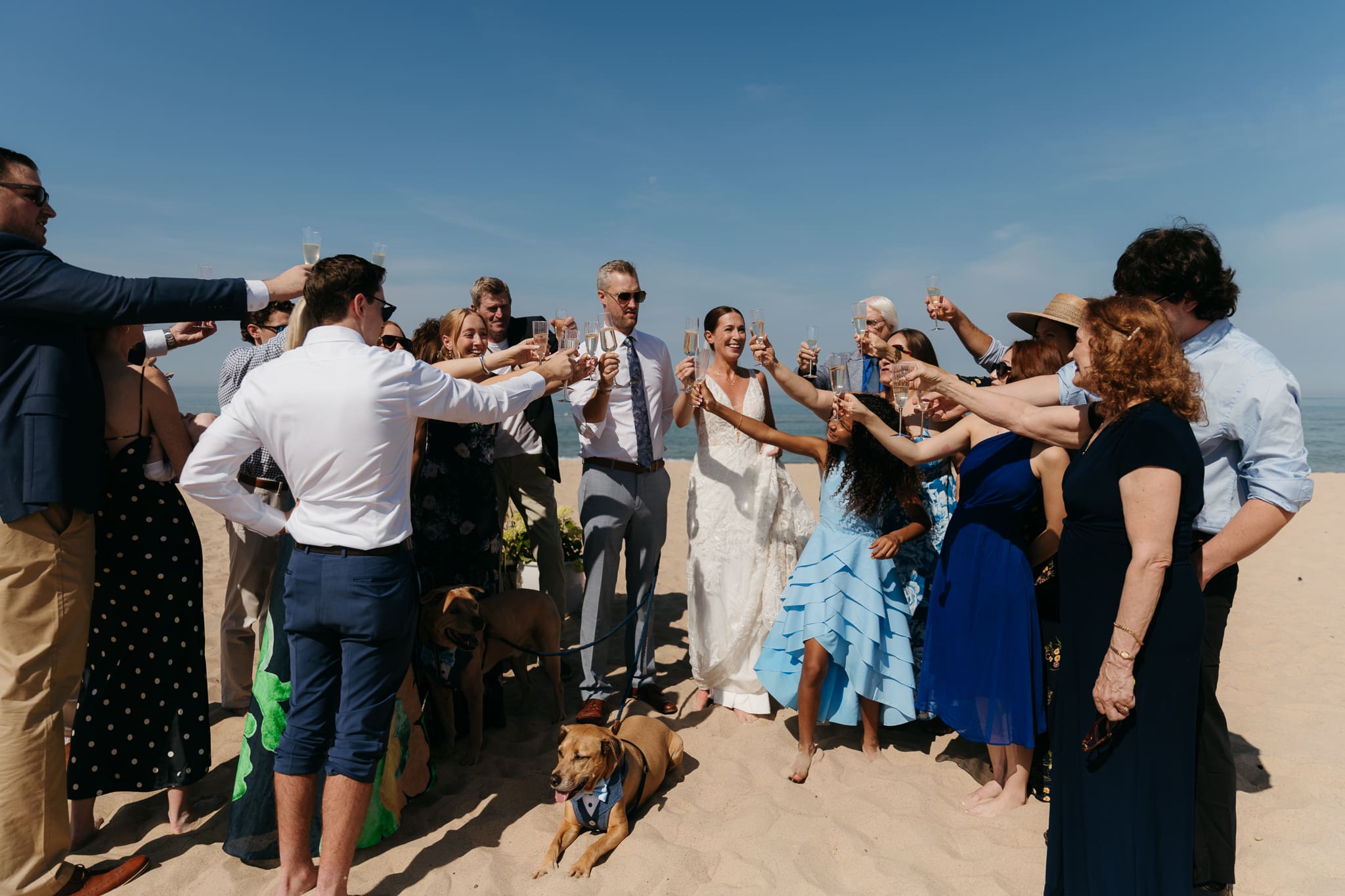 Bride and groom share champagne with guests and toast as a celebration of their marriage during their Warren Dunes elopement along the beach