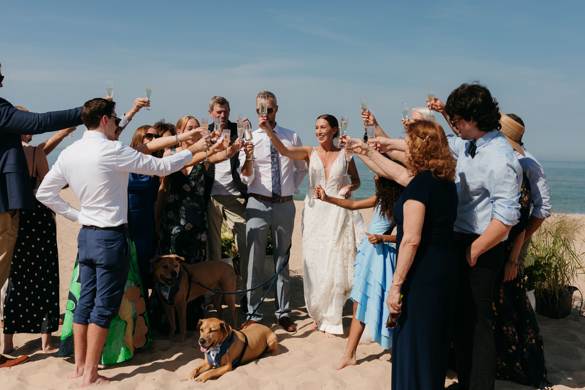 Bride and groom share champagne with guests and toast as a celebration of their marriage during their Warren Dunes elopement along the beach