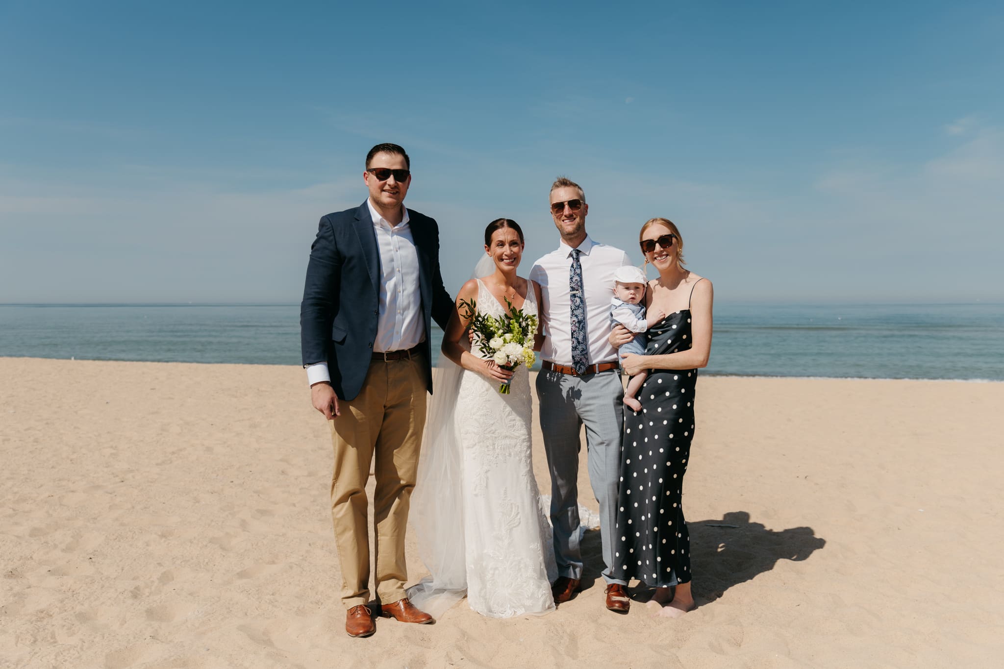 Bride and groom pose with family and friends during their Warren Dunes beach elopement along Lake Michigan