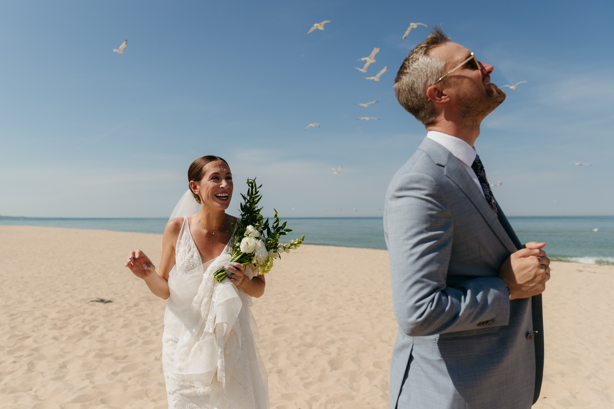 Bride and groom marvel at seagulls flying by during their Warren Dunes beach elopement along Lake Michigan