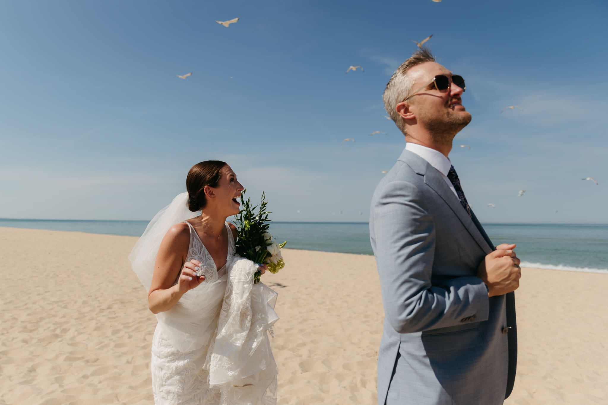 Bride and groom marvel at seagulls flying by during their Warren Dunes beach elopement along Lake Michigan