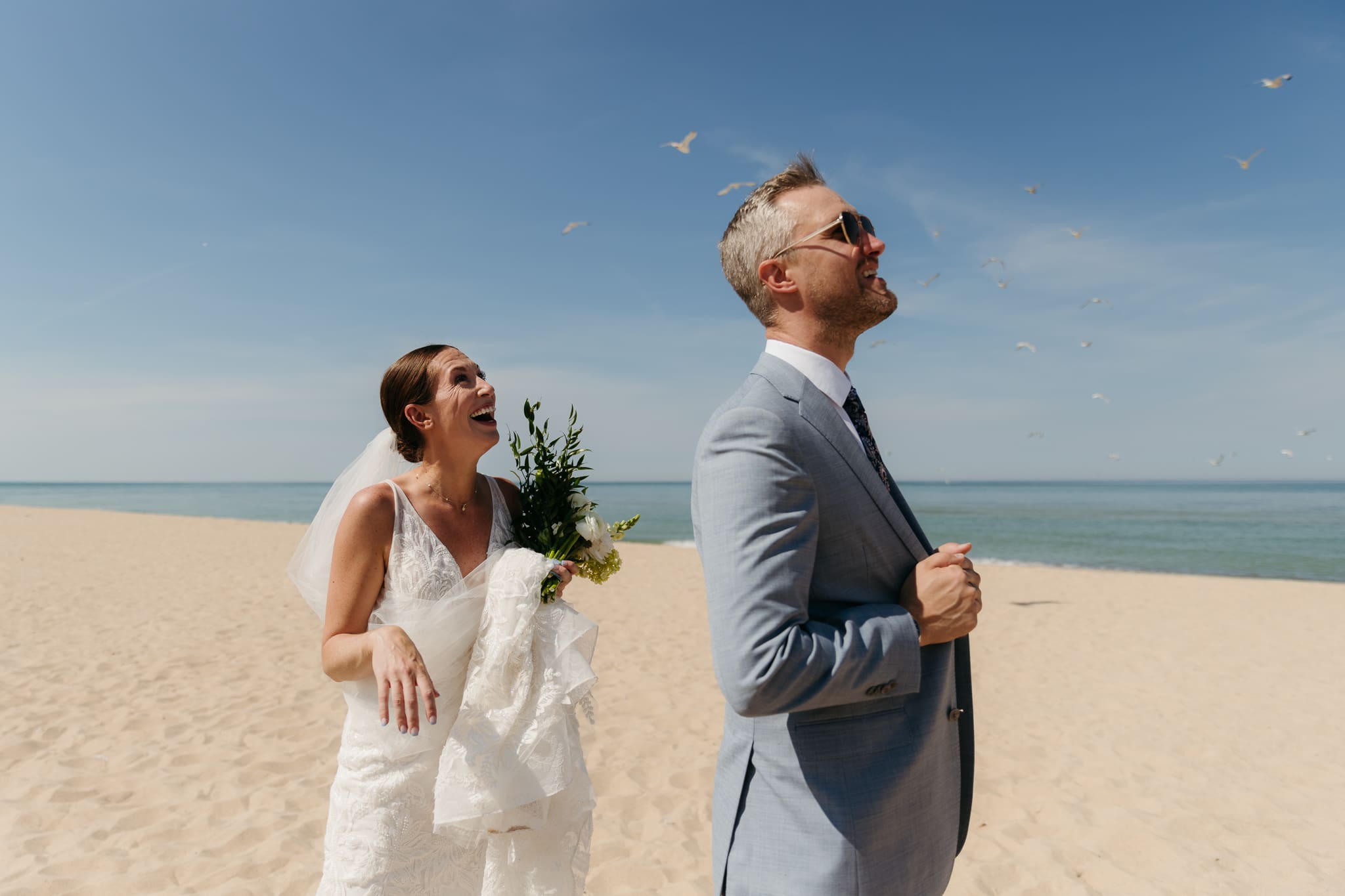 Bride and groom marvel at seagulls flying by during their Warren Dunes beach elopement along Lake Michigan