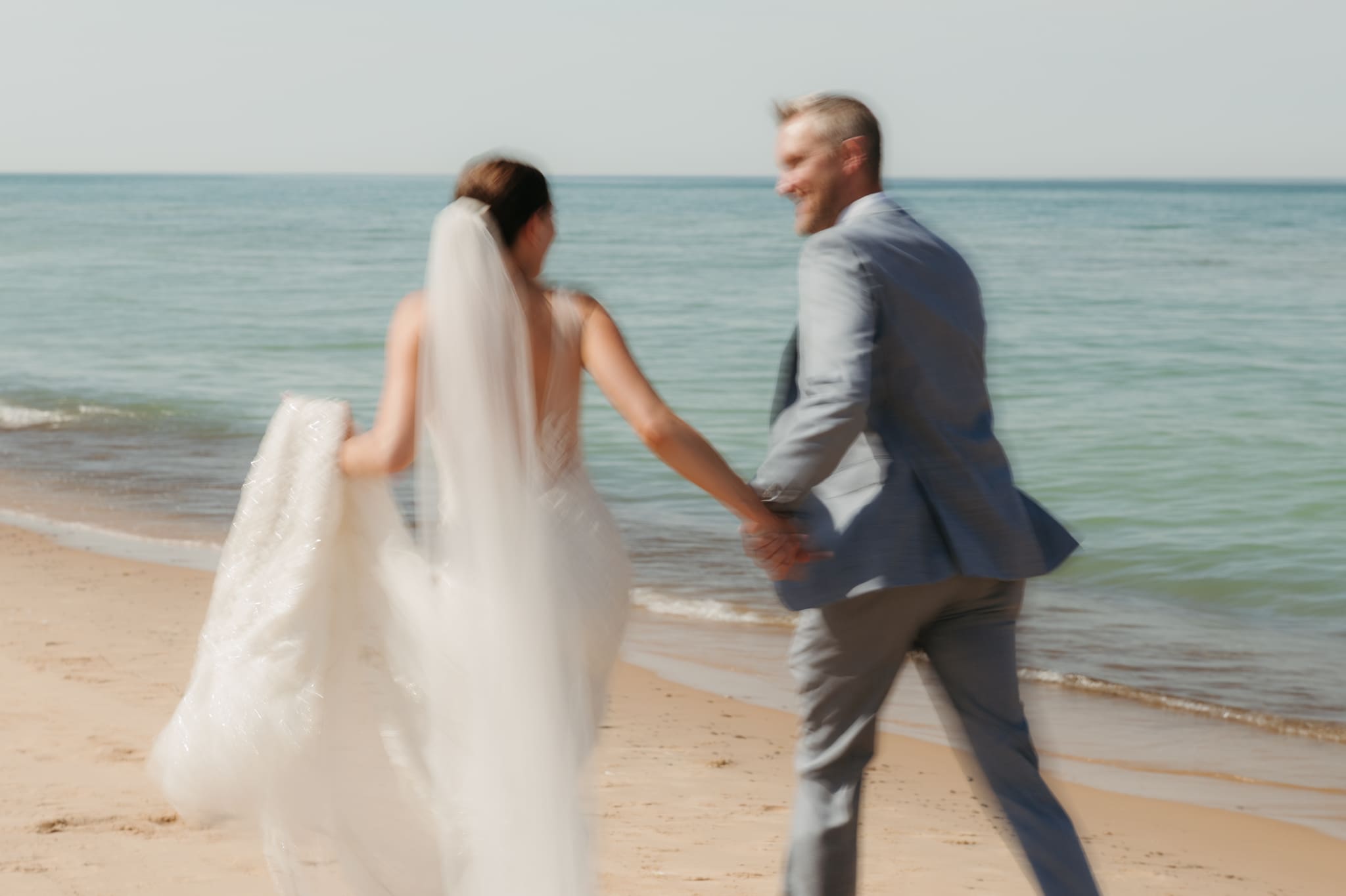 Bride and groom embracing and enjoying their Warren Dunes State Park elopement while running along the beach
