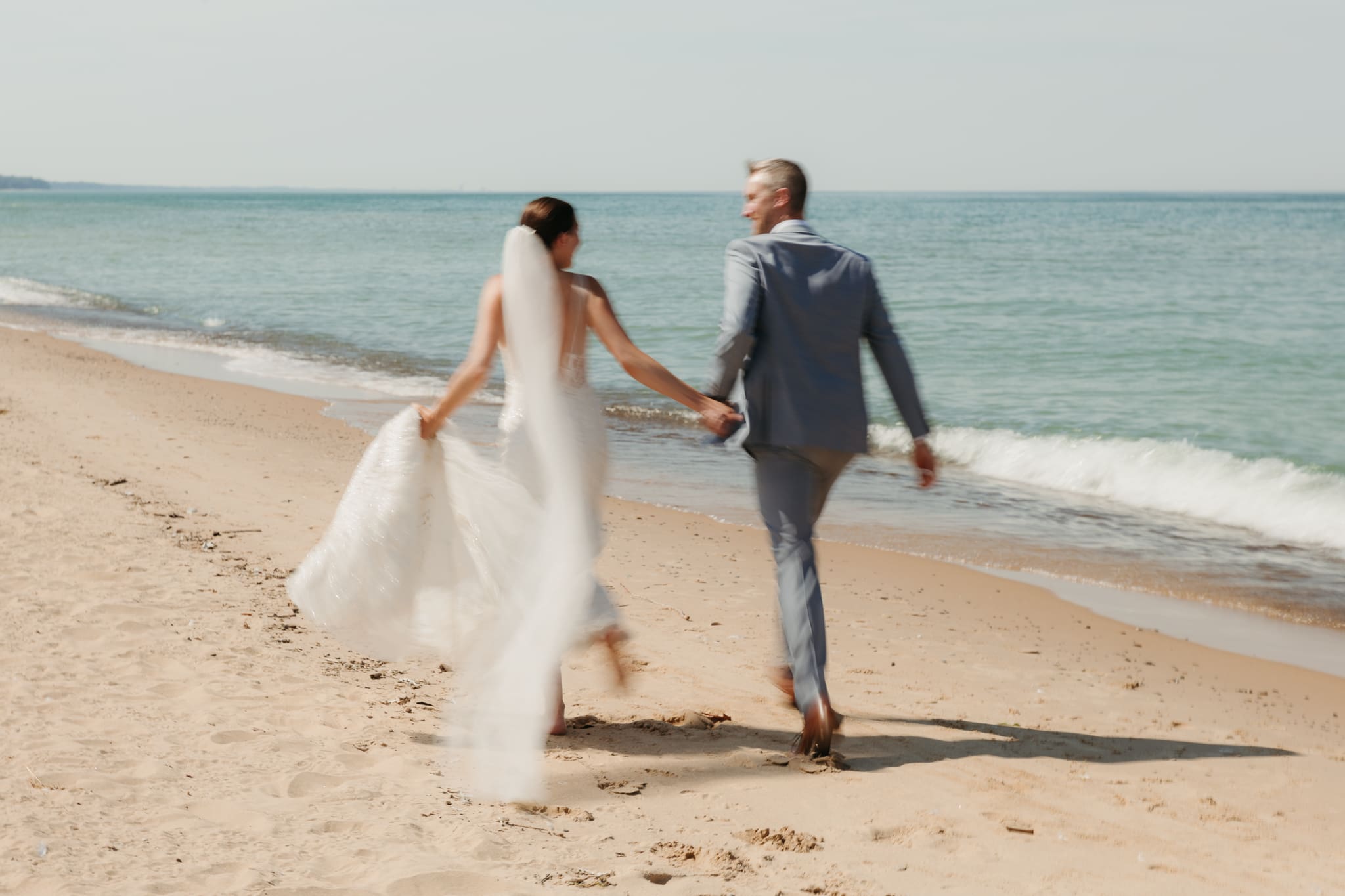 Bride and groom embracing and enjoying their Warren Dunes State Park elopement while running along the beach