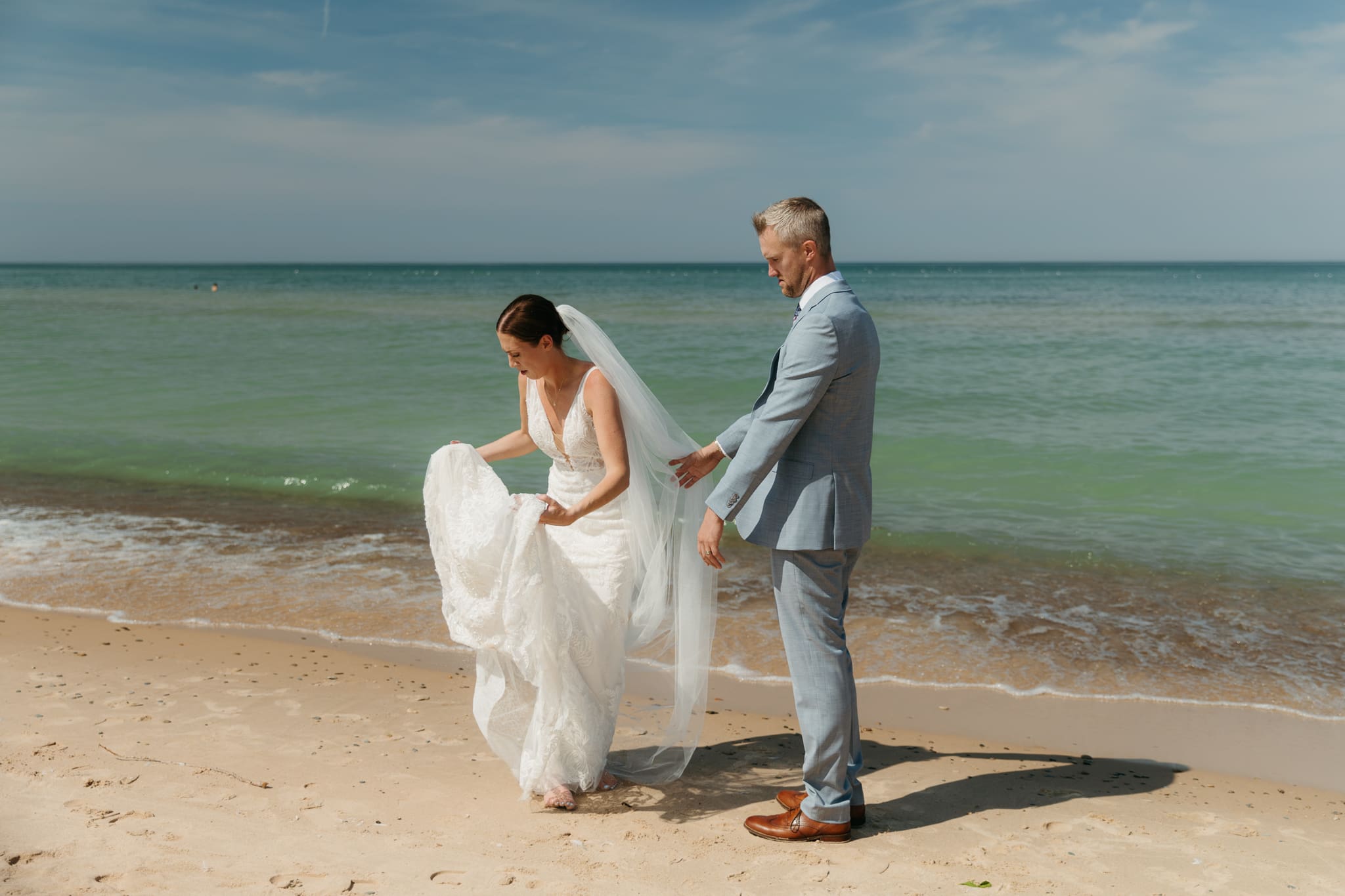 Bride and groom embrace while taking couple photos along the beach at their Warren Dunes State Park elopement