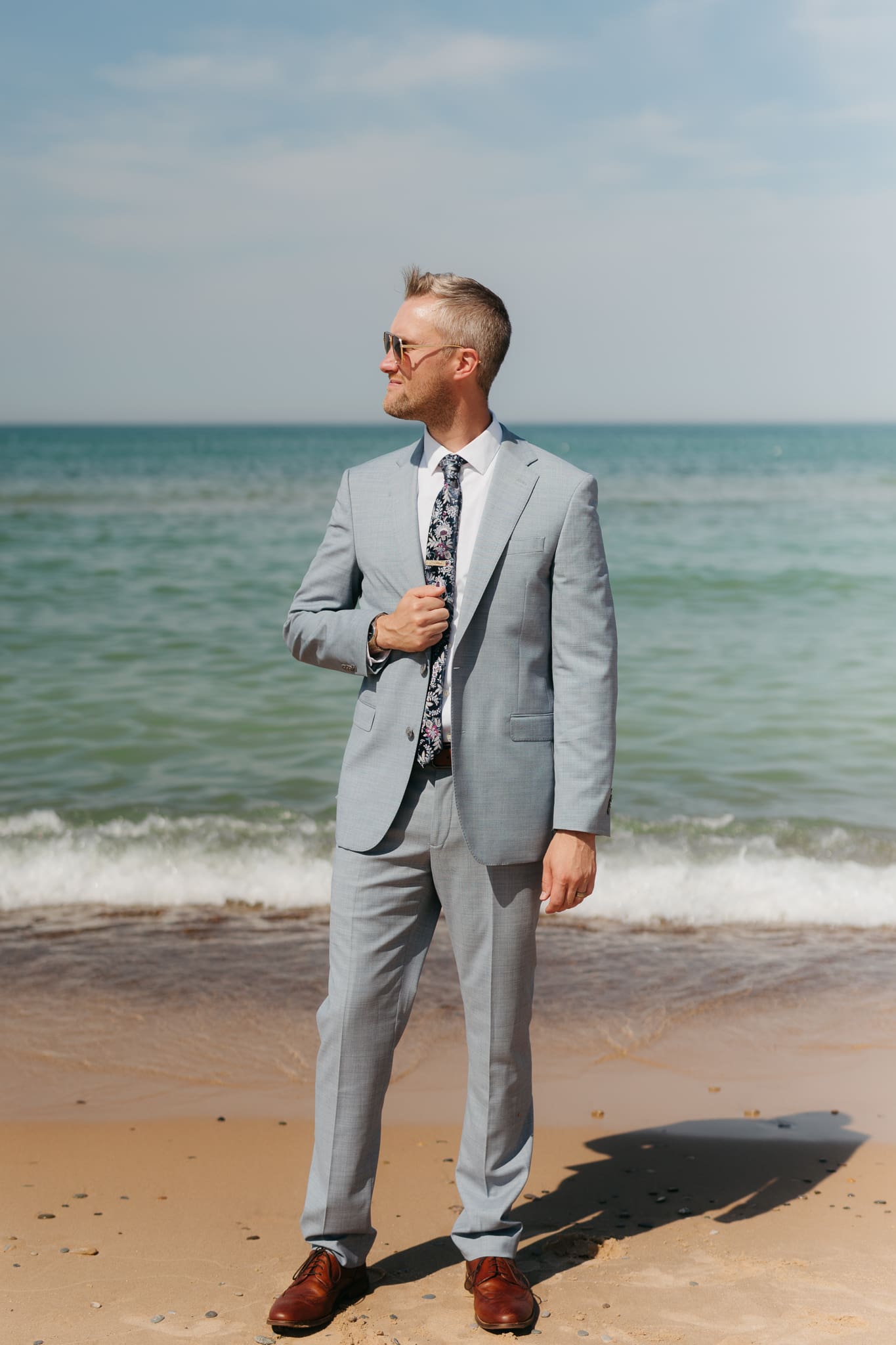 Groom poses along the shoreline of Lake Michigan