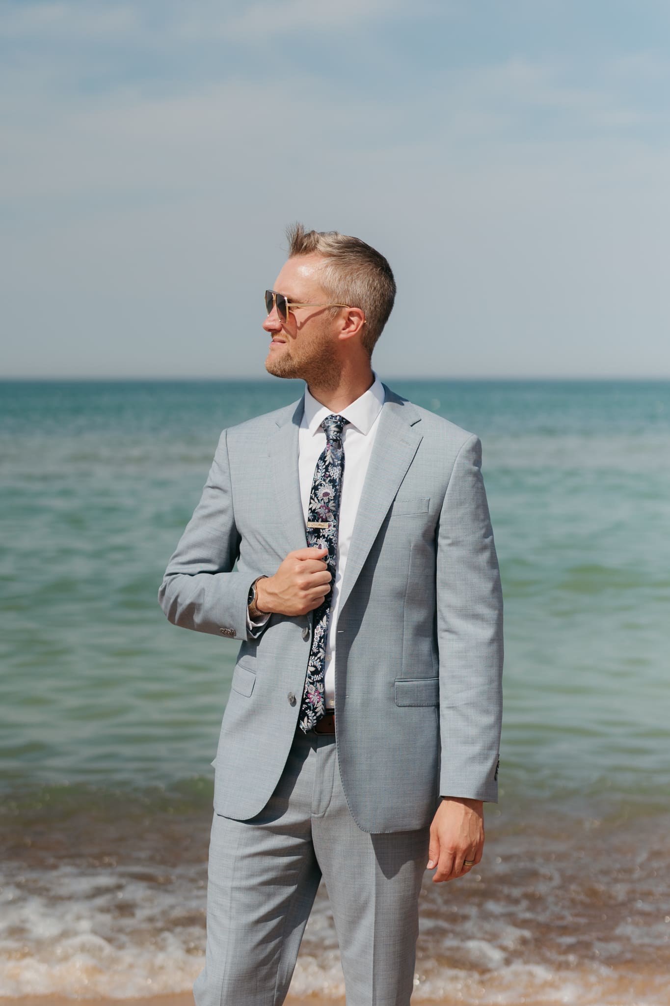 Groom poses along the shoreline of Lake Michigan