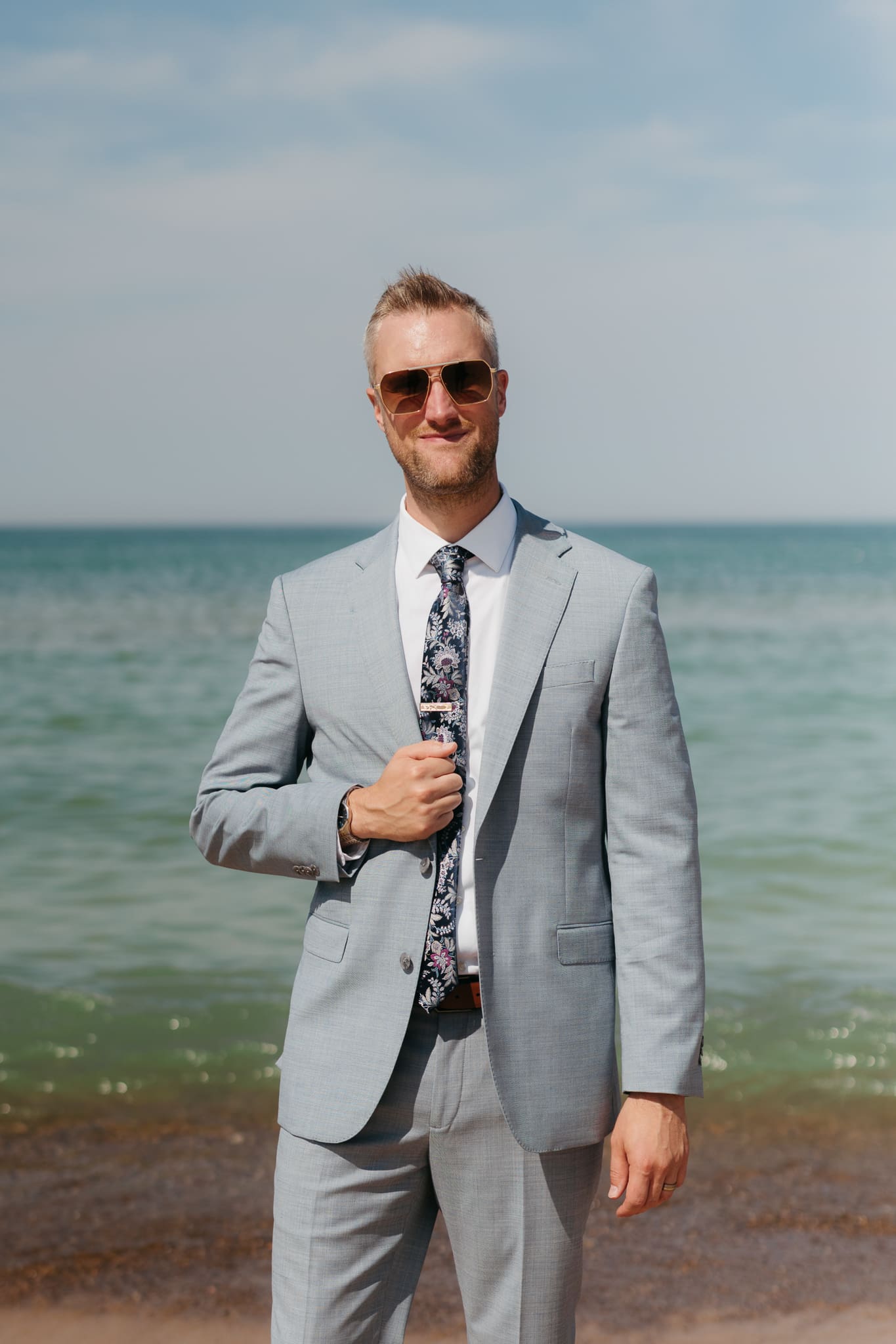 Groom poses along the shoreline of Lake Michigan