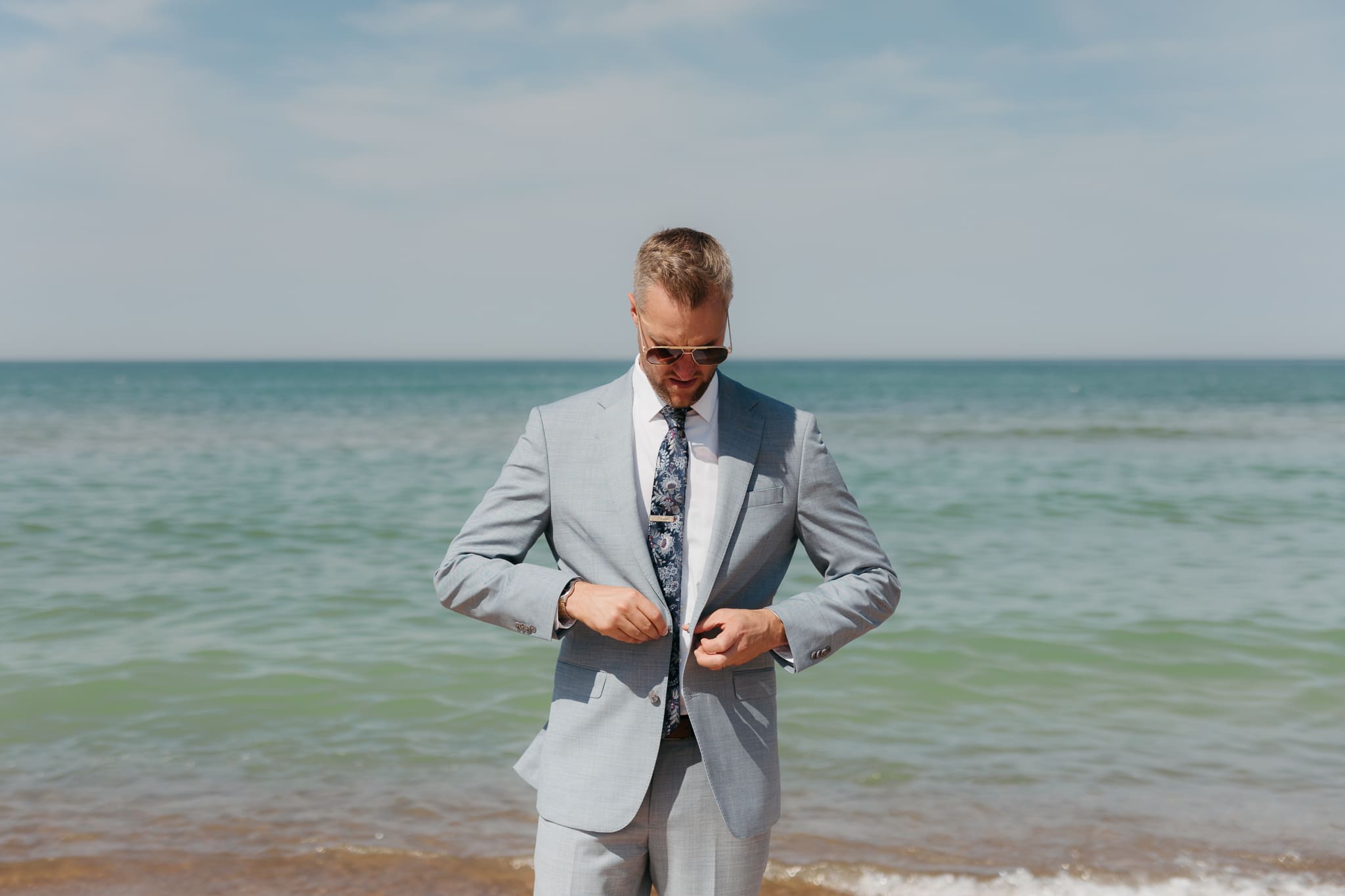 Groom poses along the shoreline of Lake Michigan