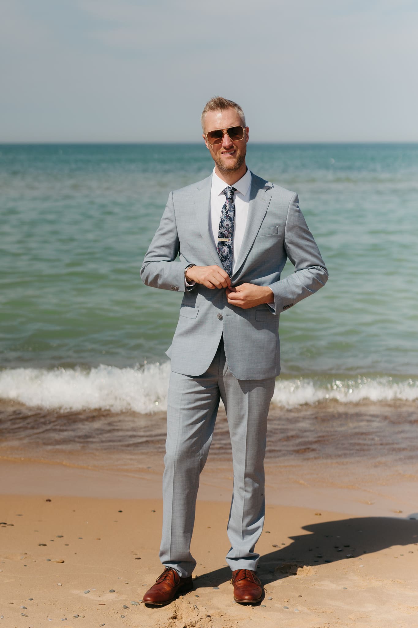 Groom poses along the shoreline of Lake Michigan