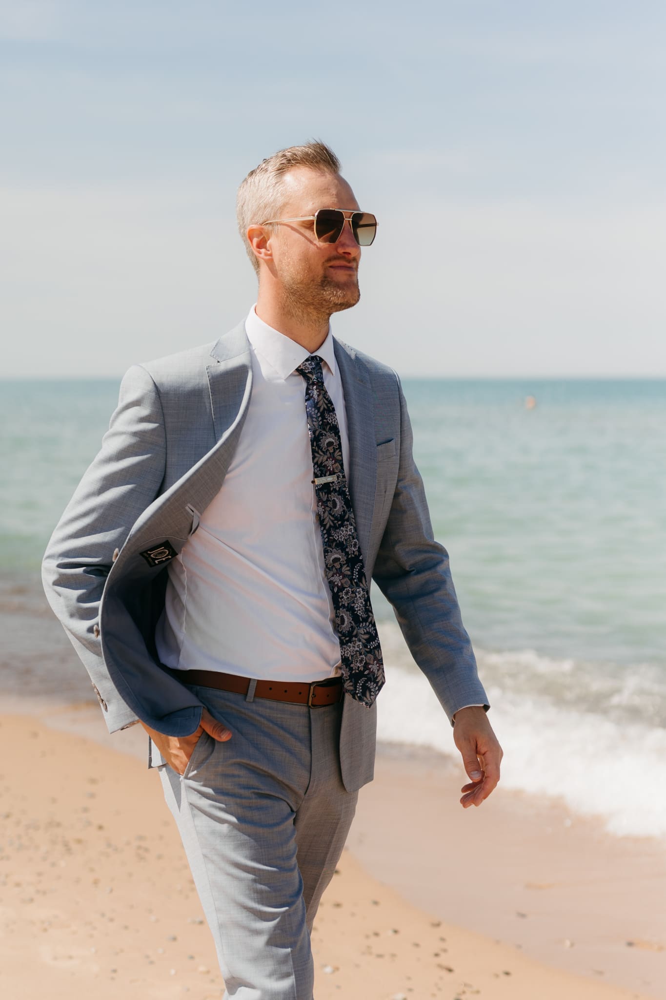 Groom poses along the shoreline of Lake Michigan