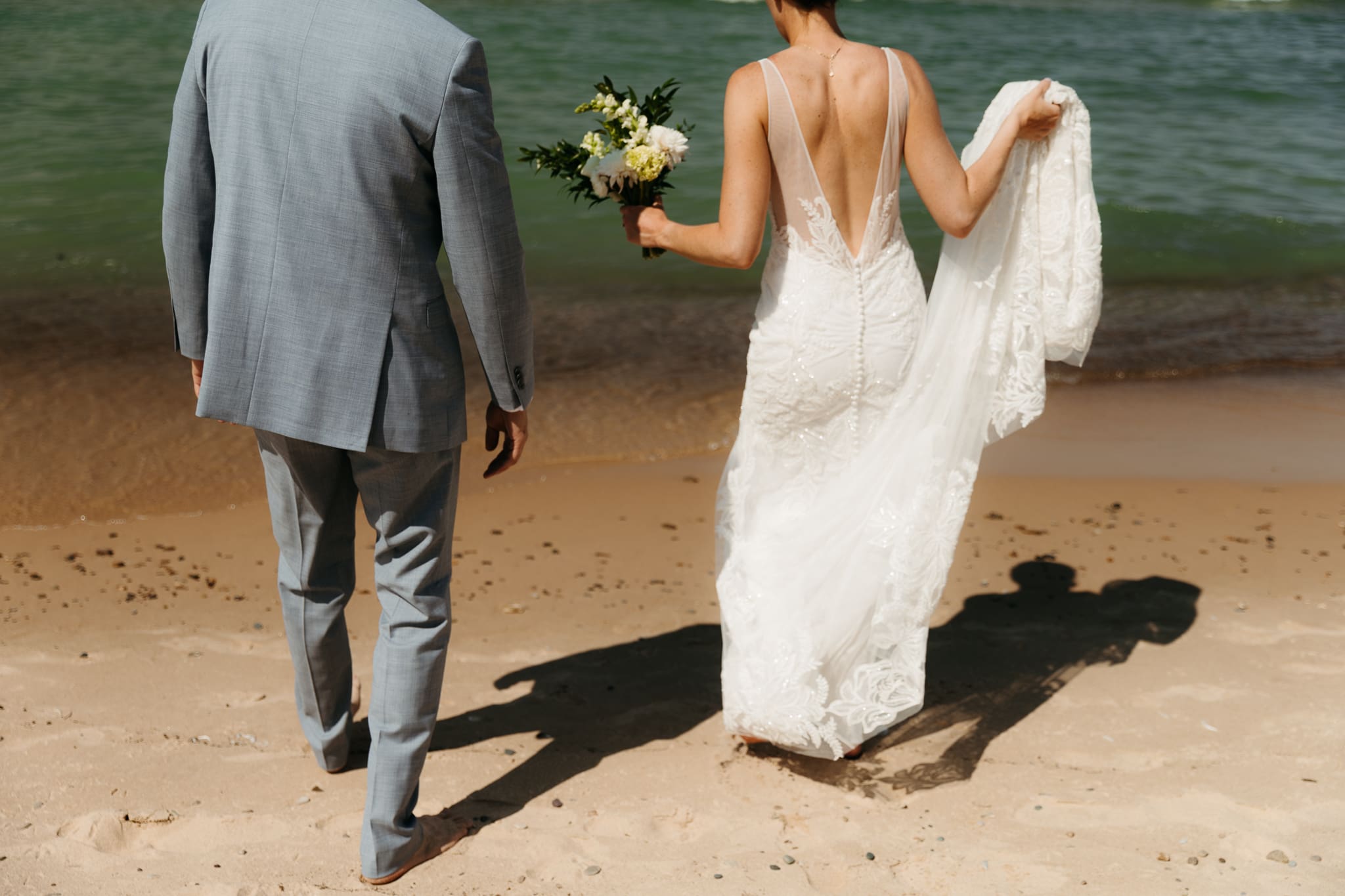 Bride and groom running along the shore of Lake Michigan during their elopement at Warren Dunes State Park