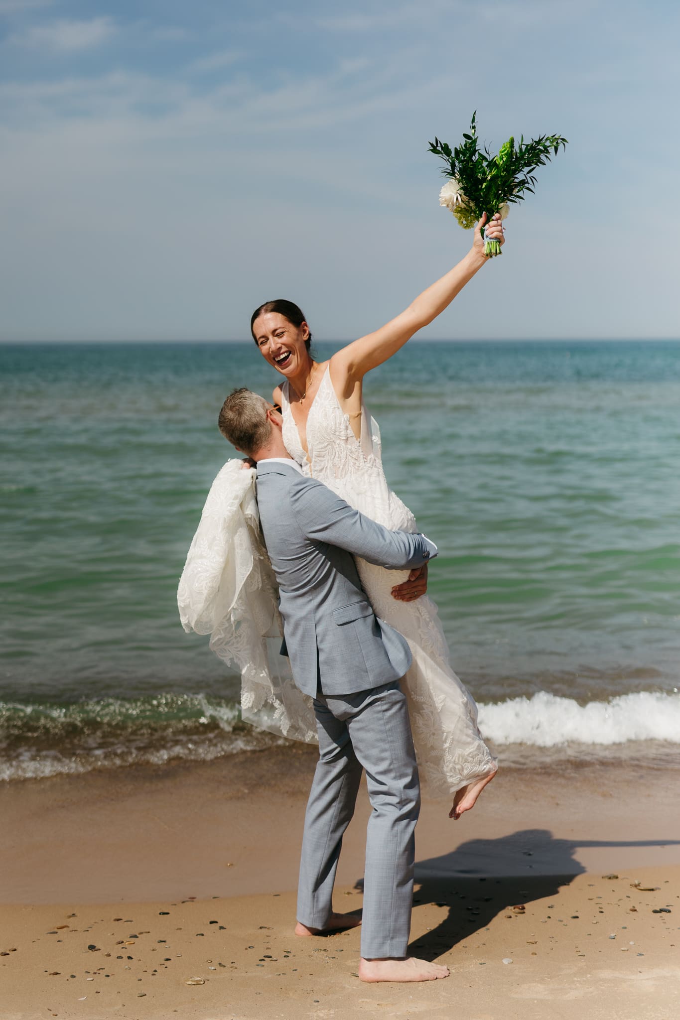 Bride and groom running along the shore of Lake Michigan during their elopement at Warren Dunes State Park