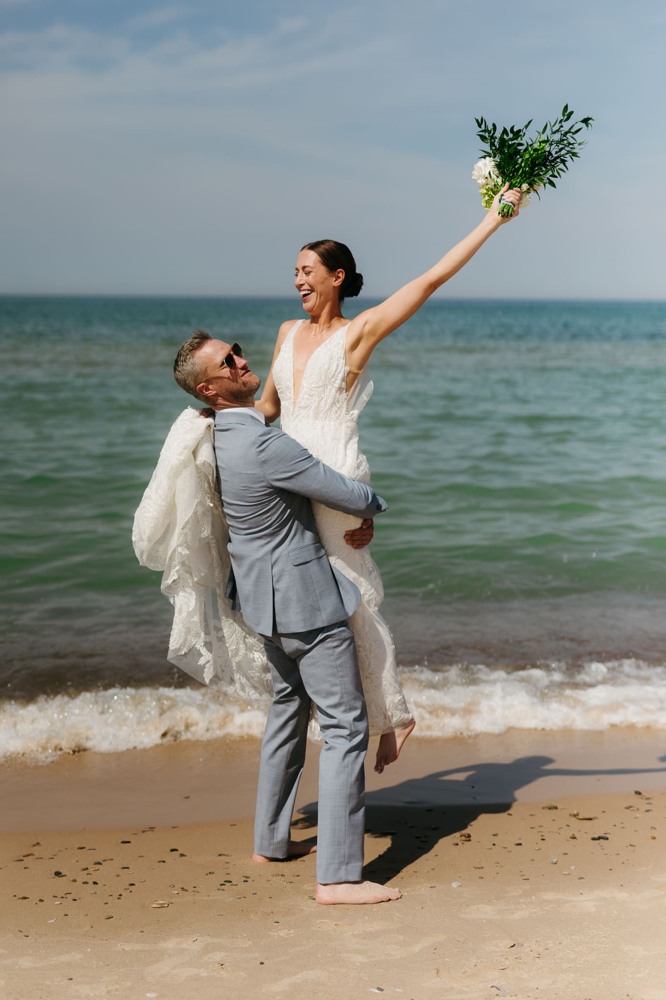 Bride and groom running along the shore of Lake Michigan during their elopement at Warren Dunes State Park
