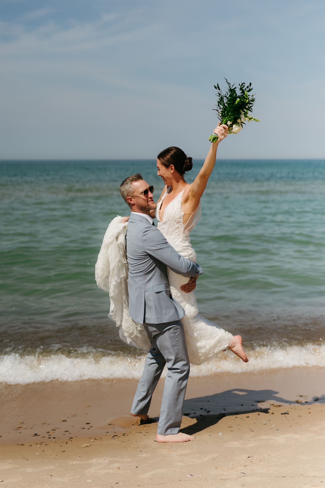 Bride and groom running along the shore of Lake Michigan during their elopement at Warren Dunes State Park
